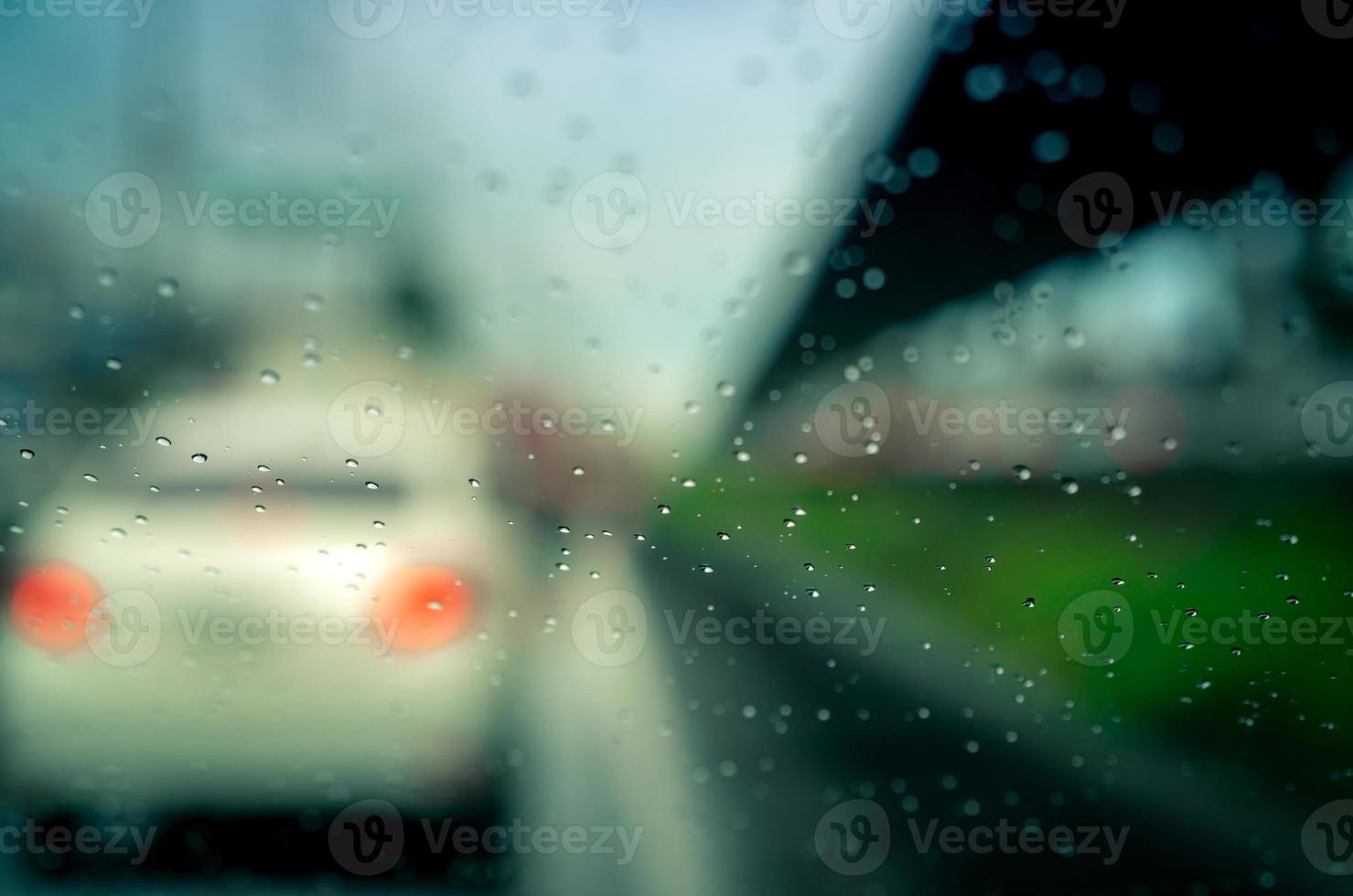 Rain drops on windshield. Car driving on asphalt road on rainy day. Windshield window of car with raindrops on glass windscreen. Traffic jam on rainy season. Bad weather in stormy day. Travel by car. photo
