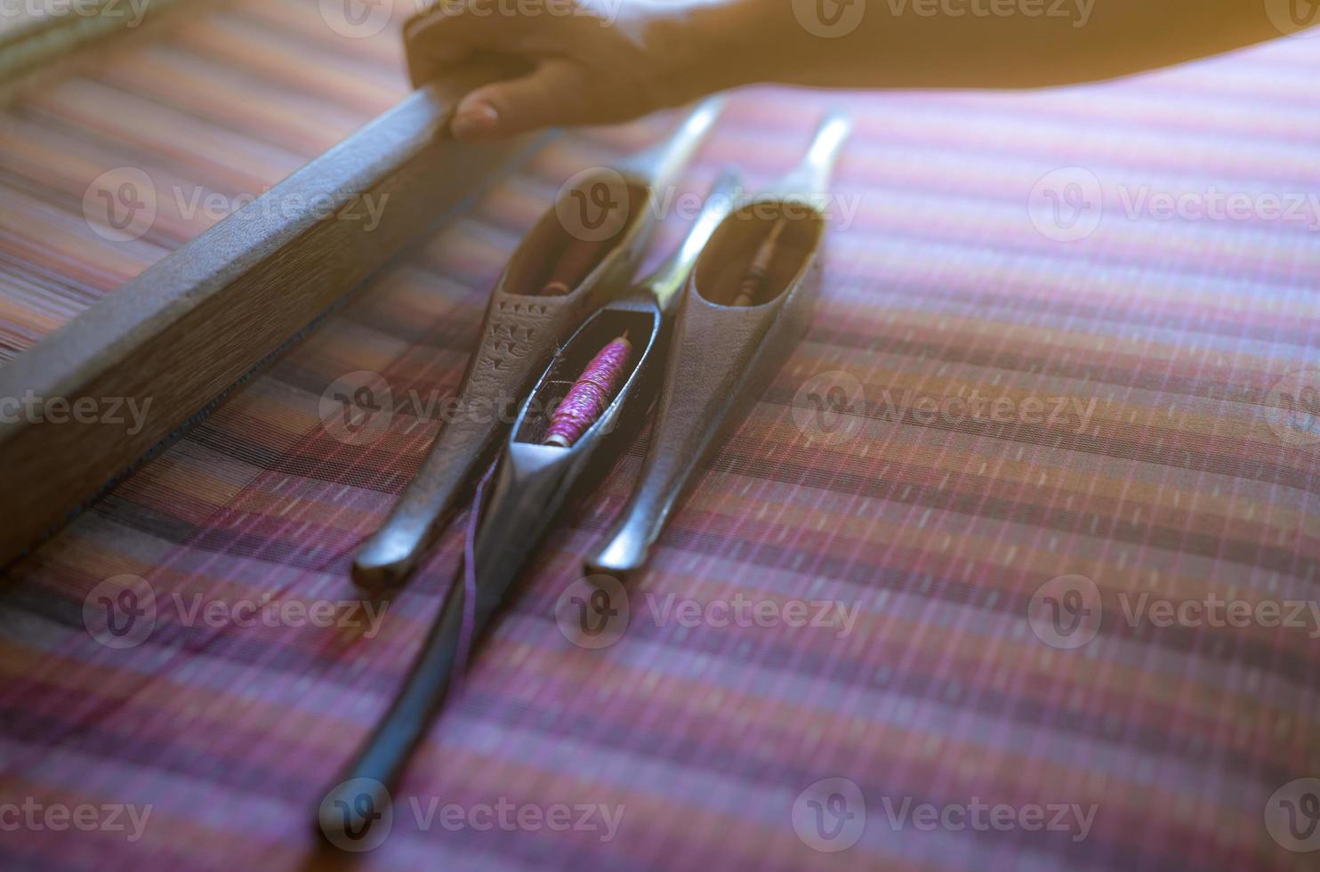 Woman working on weaving machine for weave handmade fabric. Textile weaving. Weaving using traditional hand weaving loom on cotton strands. Textile or cloth production in Thailand. Asian culture. photo