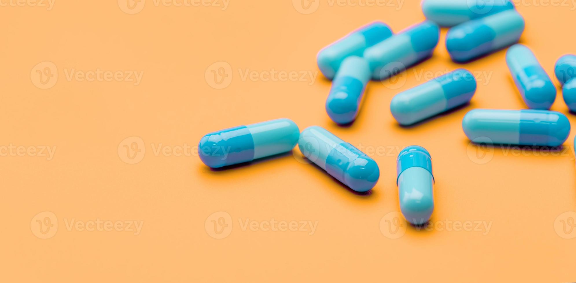 Blue antibiotic capsule pills spread on yellow background. Antibiotic drug resistance. Pharmaceutical industry. Healthcare and medicine concept. Health budget concept. Capsule manufacturing industry. photo