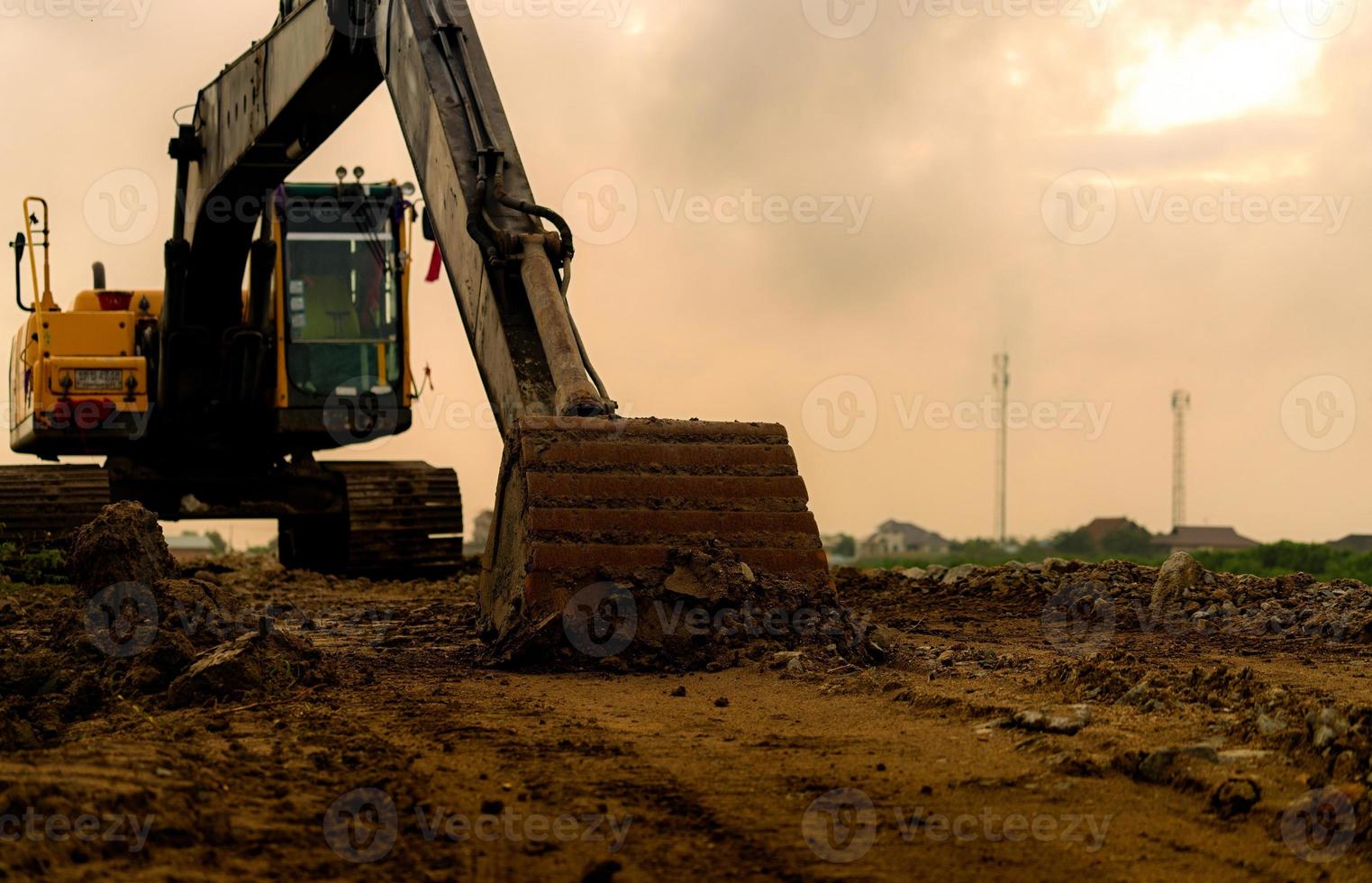 Backhoe parked at construction site after digging soil. Closeup bucket of bulldozer. Digger after work. Earth moving machine at construction site of housing estate. Digger with dirt bucket and soil. photo