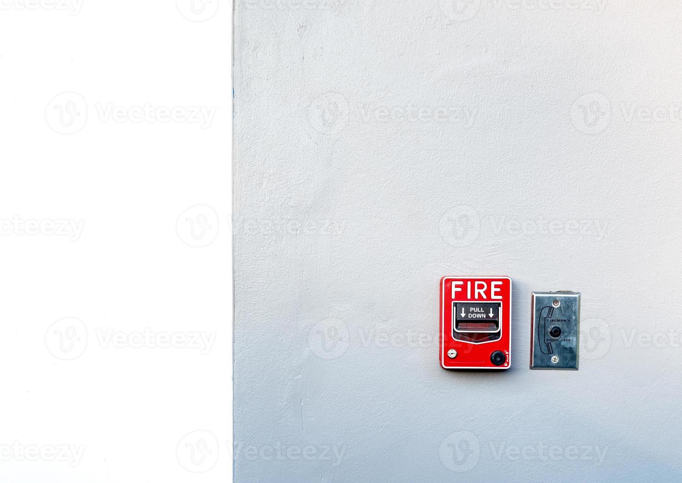 Fire alarm on white concrete wall. Warning and security system. Emergency equipment for safety alert. Red box of fire alarm on wall of school, hospital, factory, office, apartment, or home. Pull down. photo