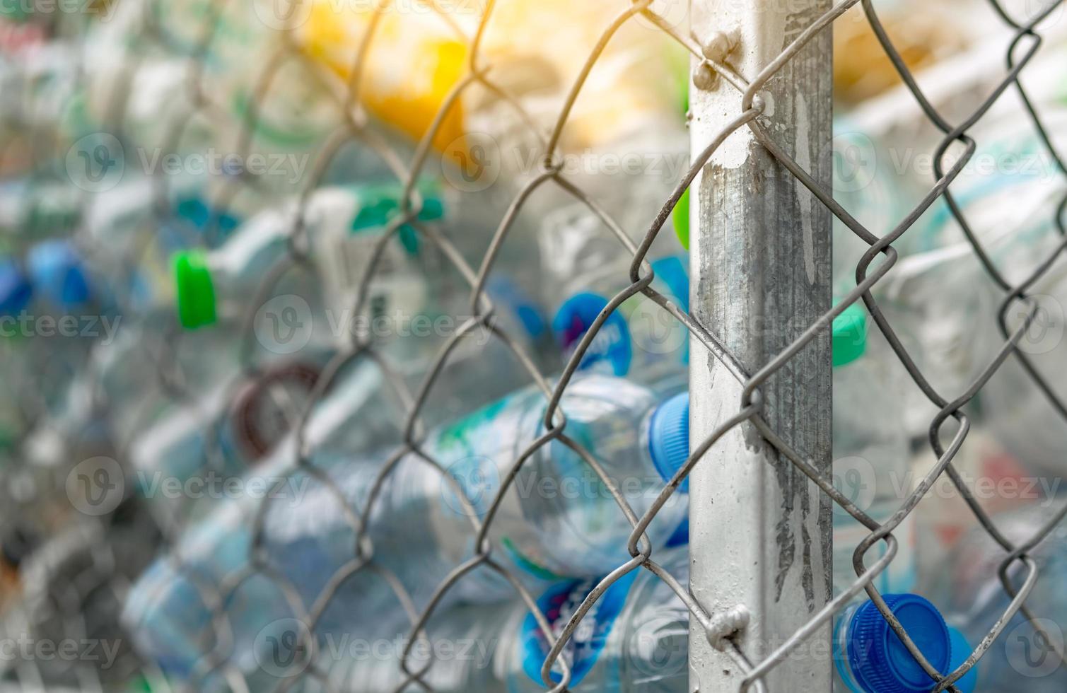 Blurred pile of empty water plastic bottle in mesh fence recycle bin. Plastic bottle waste for recycle in recycling business. Plastic waste management. Reduce and reuse plastic concept. PET rubbish. photo