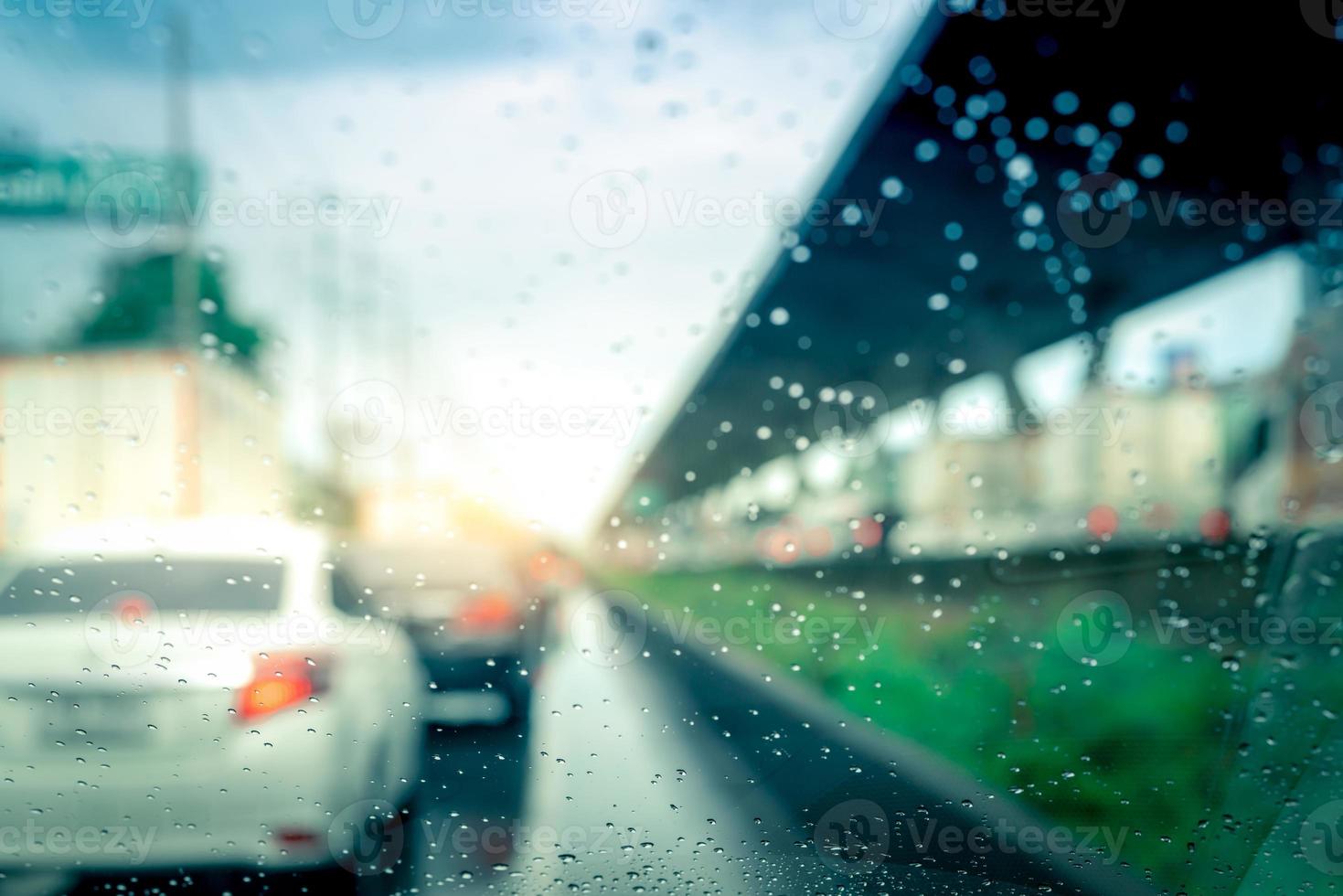 Rain drops on windshield. Car driving on asphalt road on rainy day. Windshield window of car with raindrops on glass windscreen. Traffic jam on rainy season. Bad weather in stormy day. Travel by car. photo