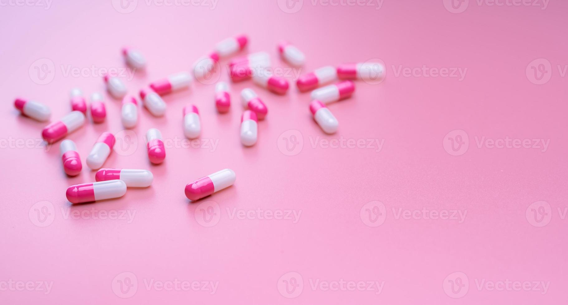 Pink-white antibiotic capsules pill spread on pink background. Pharmacy banner. Antibiotic resistance concept. Pills and love concept. Pharmaceutical industry. Pharmacy and health insurance business. photo