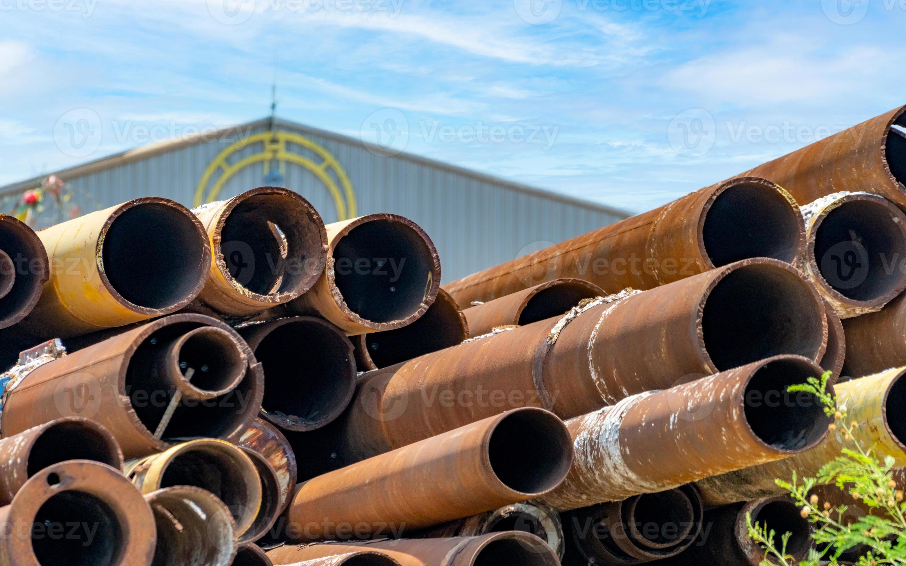 Pile of old rusty round metal industrial pipe. Steel pipe stack at