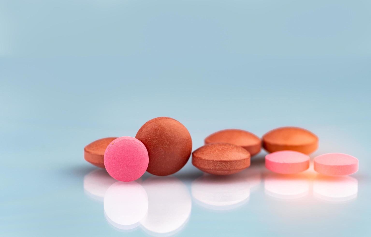 Selective focus on orange and pink round tablets with shadow on gradient background. Pharmaceutical industry. Pharmacy products. Vitamins and supplements concept. Tablets pills texture background. photo