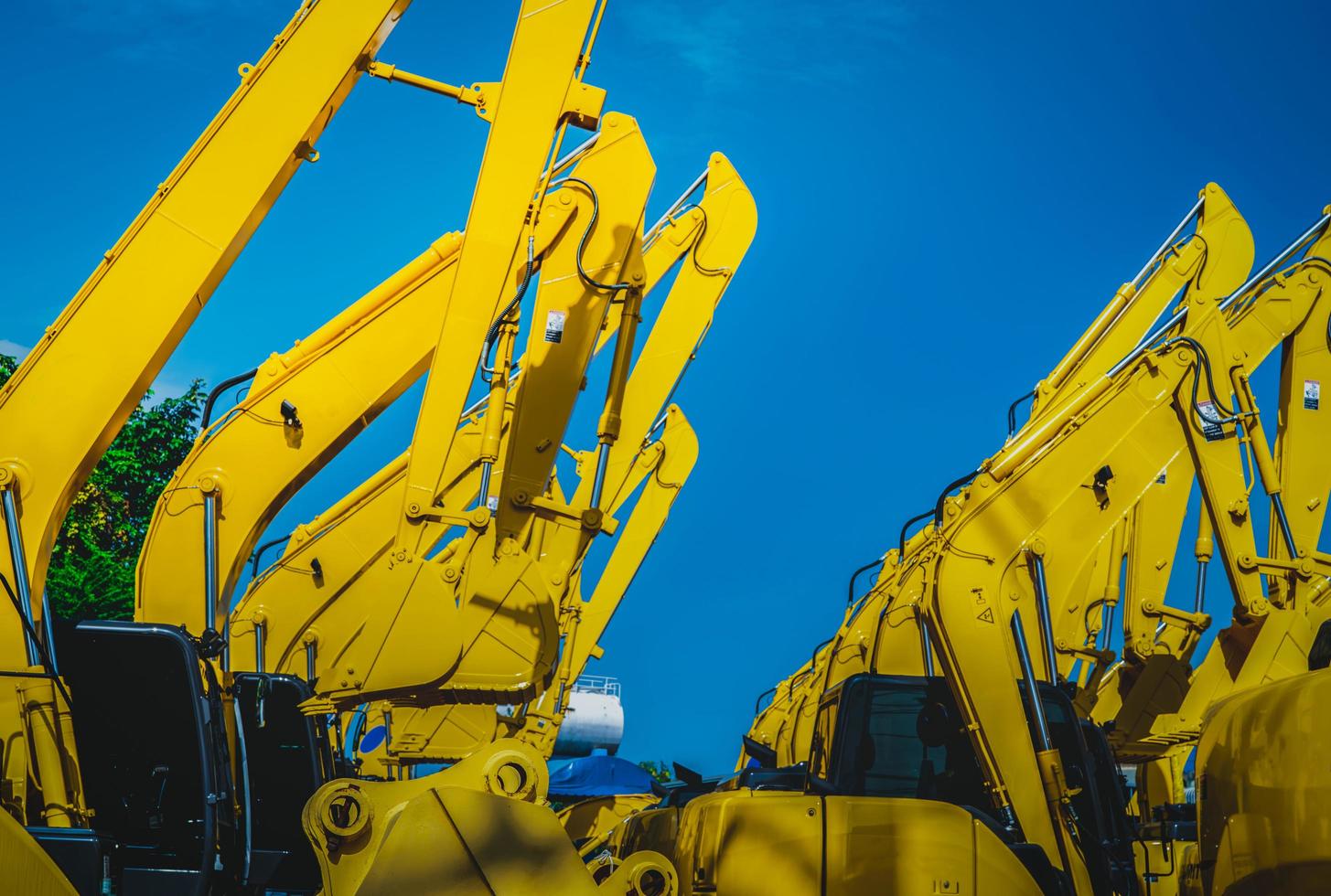 Yellow backhoe with hydraulic piston arm against clear blue sky. Heavy machine for excavation in construction site. Hydraulic machinery. Huge bulldozer. Heavy industry photo