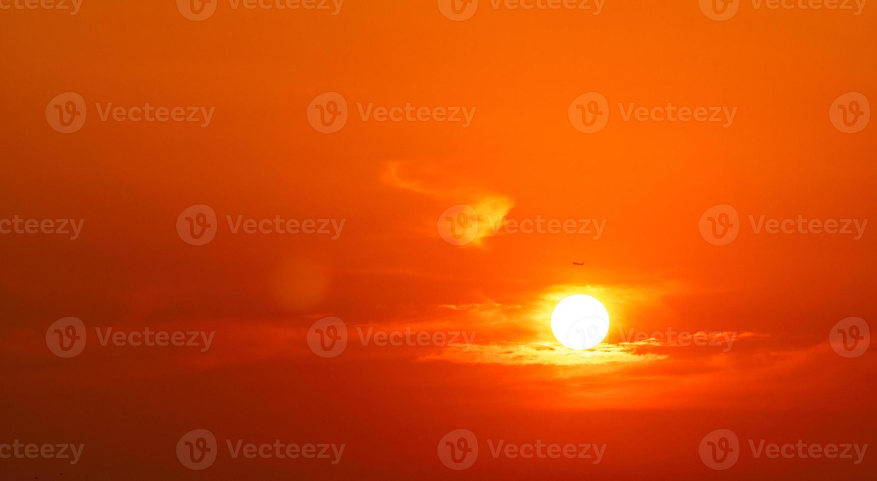 Dramatic red and orange sky and clouds abstract background. Airplane flying near big sun at sunset. Art picture of sky at dusk. Sunset abstract background. Commercial airline in the evening flight. photo