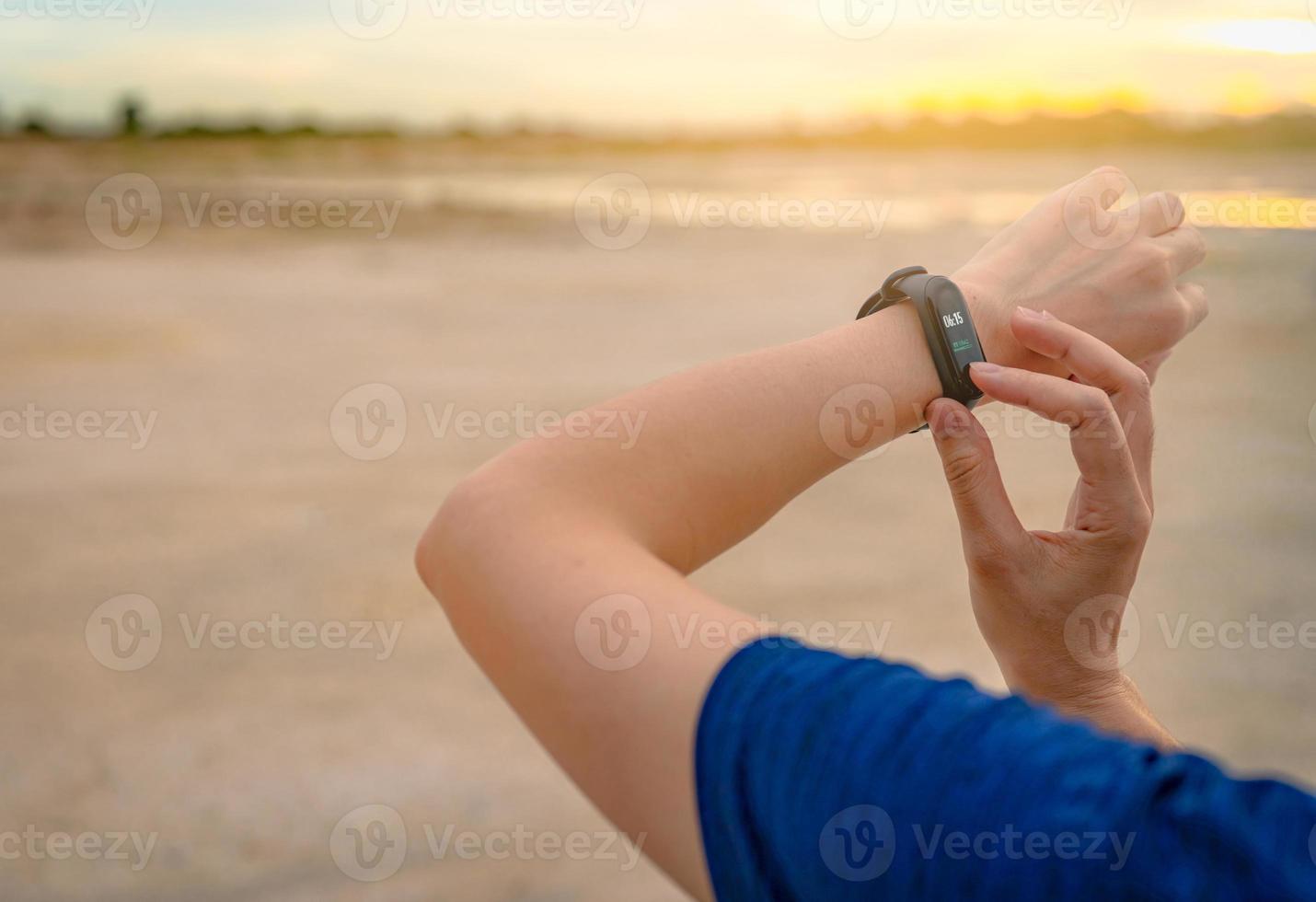 Young Asian woman touching smart band after running in the morning. Wearable computer. Heart rate monitor bracelet. Fitness device. Activity or fitness tracker. Smart watch connected device. Wristband photo