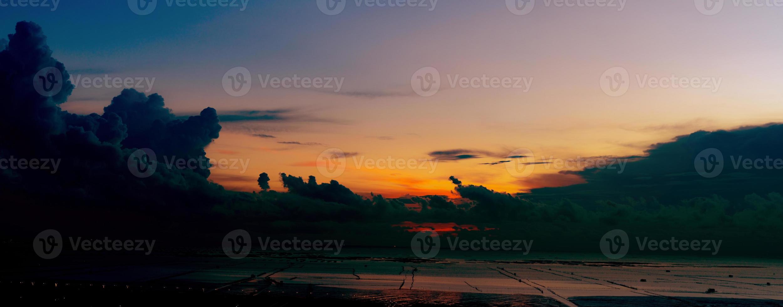 Panorama view of sea at tide and silhouette dramatic sunset sky and clouds in the evening with light on the road at seaside of the city. Summer sunset sky of tropical paradise beach. Beauty in nature. photo