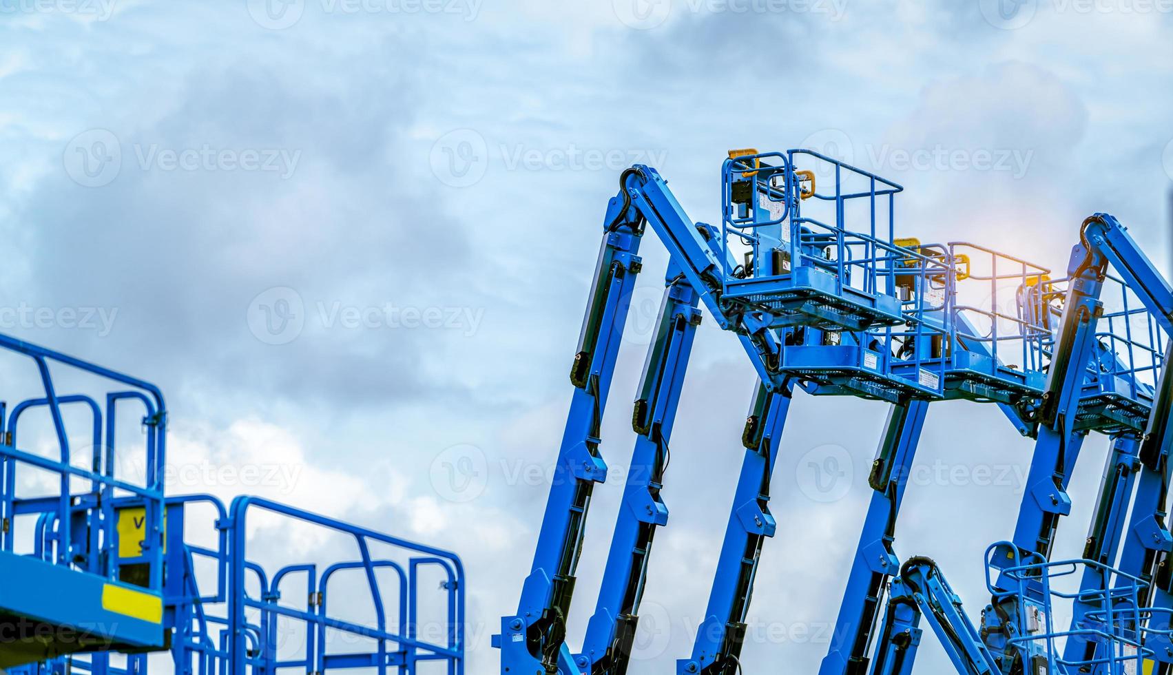 Articulated boom lift. Aerial platform lift. Telescopic boom lift against blue sky. Mobile construction crane for rent and sale. Maintenance and repair hydraulic boom lift service. Crane dealership. photo