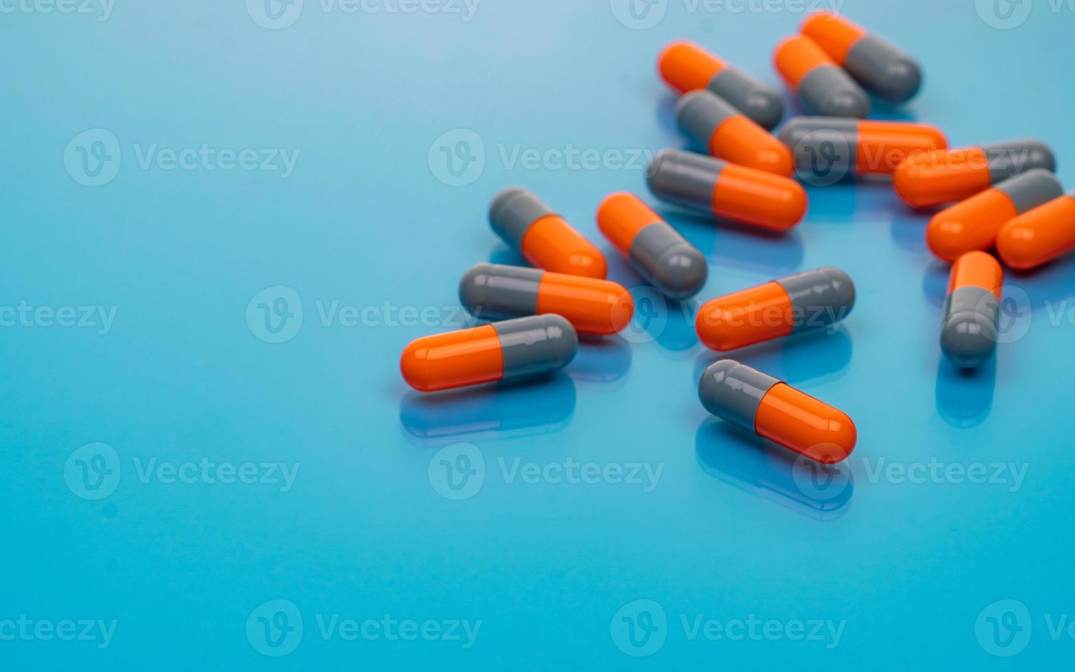 píldoras de cápsula antibiótica de color gris anaranjado sobre fondo azul. resistencia a los antibióticos. industria farmacéutica. medicamento con receta médica. Fabricación de producción de píldoras de cápsulas. farmacología y toxicología. foto