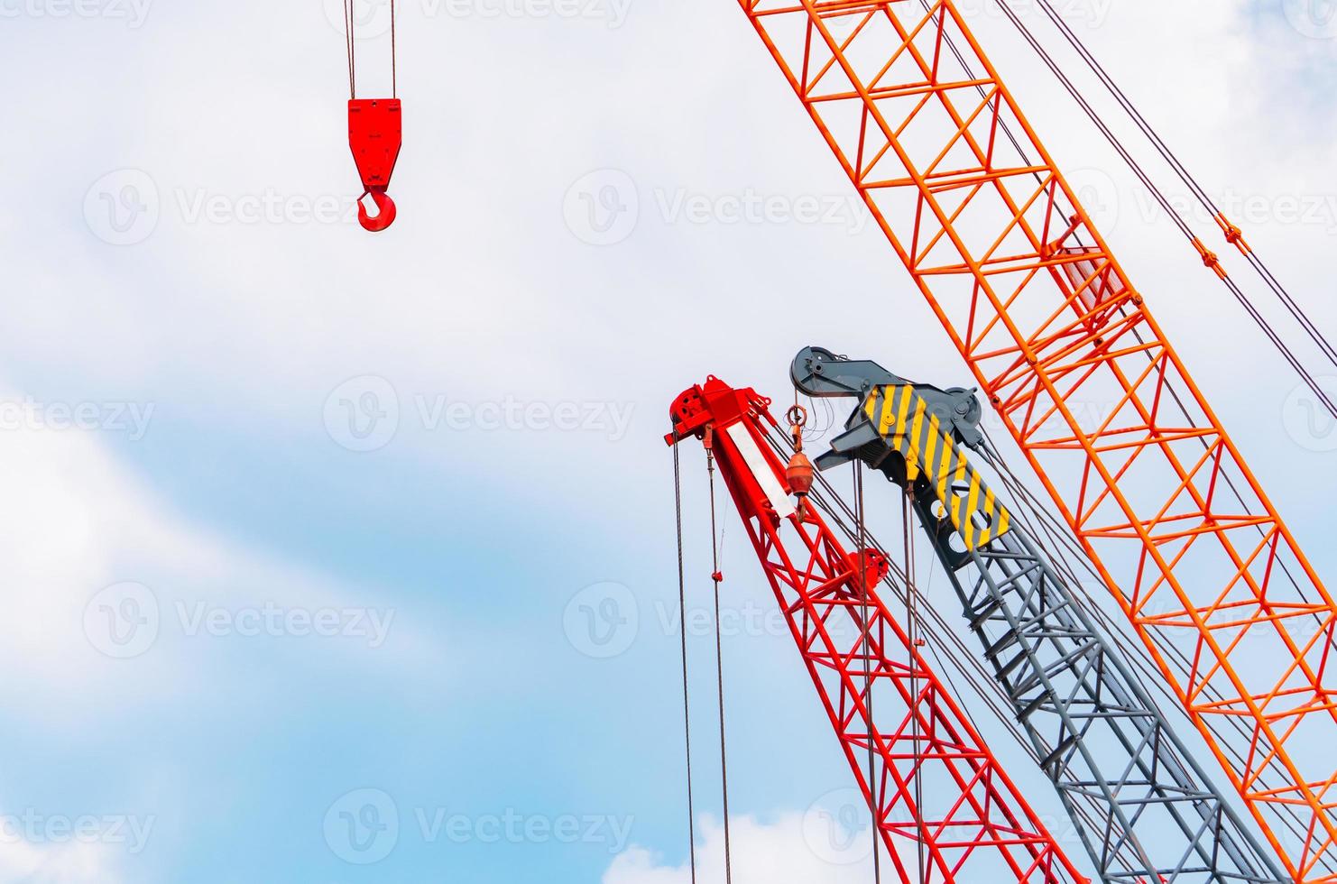 Crawler crane against blue sky and white clouds. Real estate industry. Red crawler crane use reel lift up equipment in construction site. Crane for rent. Crane dealership for construction business. photo