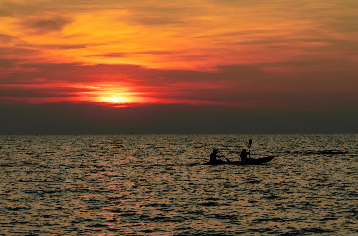 la silueta de la pareja está navegando en kayak en el mar al atardecer. kayak en el mar tropical al atardecer. pareja romántica viaja en vacaciones de verano. actividades de aventura de parejas románticas. hermoso cielo al atardecer. foto