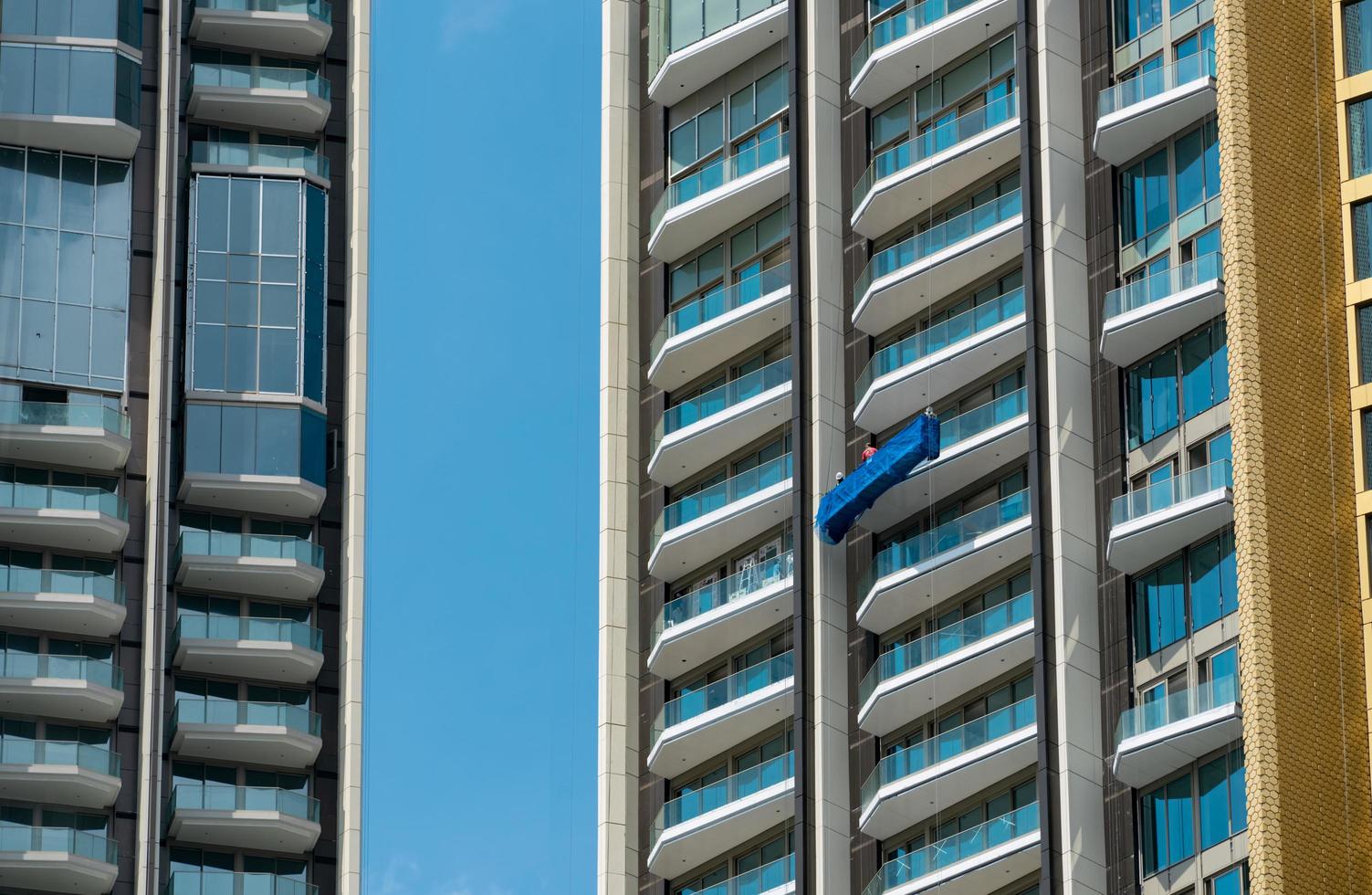 High rise window cleaner with cradle lift. Glass cleaner is working. Dangerous jobs in the building, cleaning and maintenance industries. Cleaning windows service. High risk work. Exterior building. photo