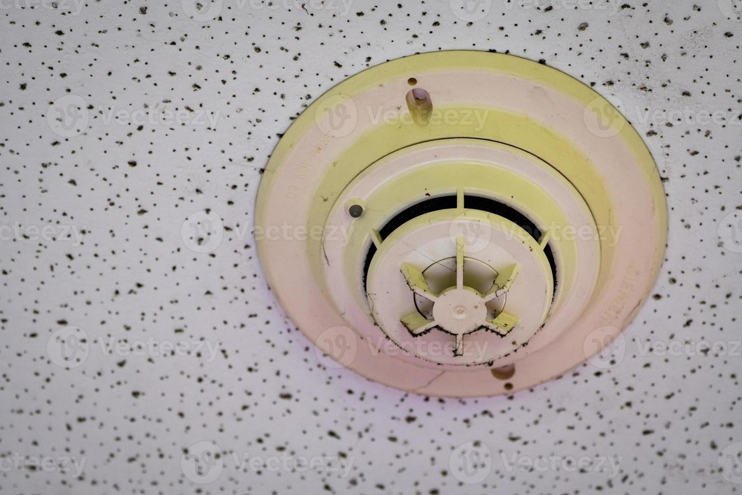 Old and dirty smoke detector with cobwebs on ceiling wall. Fire alarm system in house doesn't work. Emergency equipment in apartment need to clean and maintenance service. Carbon monoxide sensor. photo