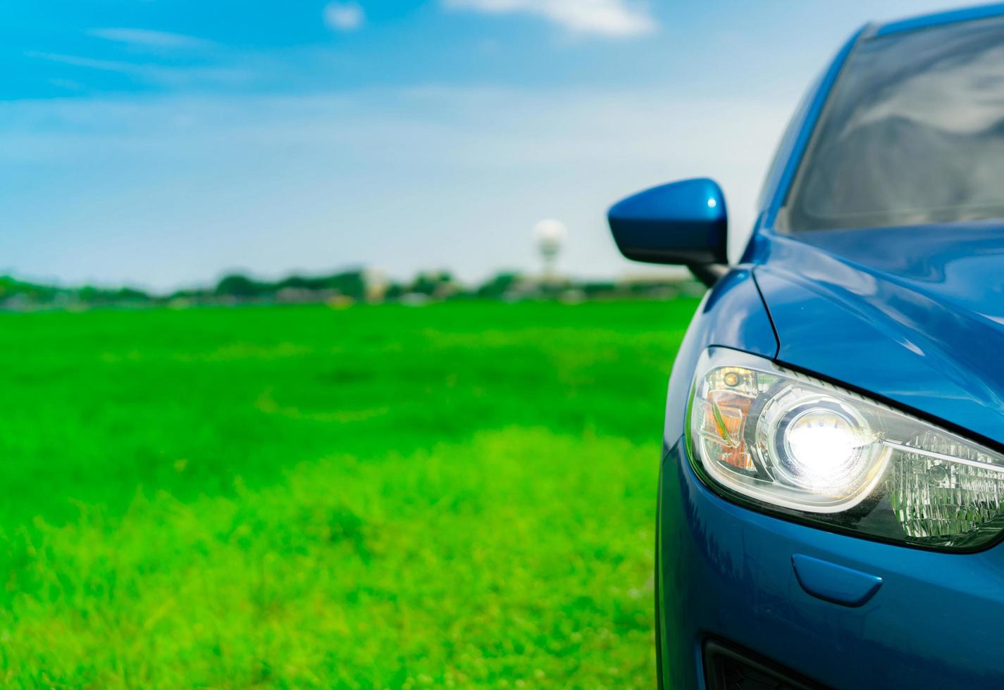 vista frontal de un lujoso camión suv compacto azul con diseño deportivo y moderno estacionado en un campo de hierba verde con cielo azul y nubes blancas. automóvil híbrido y automotriz. viaje por carretera y conducción de automóviles para viajar. foto