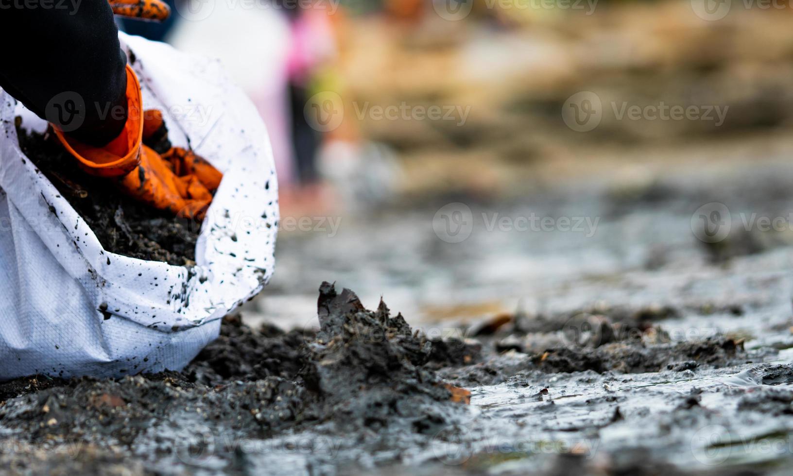 Volunteers collecting garbage. Beach environment pollution. Volunteers cleaning the beach on blurred background. Tidying up rubbish on beach. Oil stains on the beach. Oil leak to the sea. photo