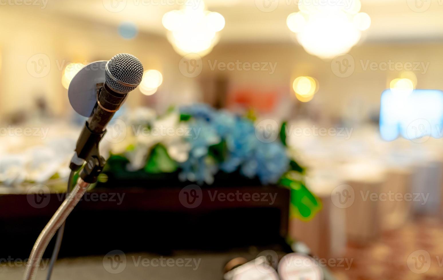 Microphone on stand at podium stage for public speaking or speech in conference hall. Mic for speaker on stage of event. Meeting and presentation in seminar room. Microphone for talking to audience. photo