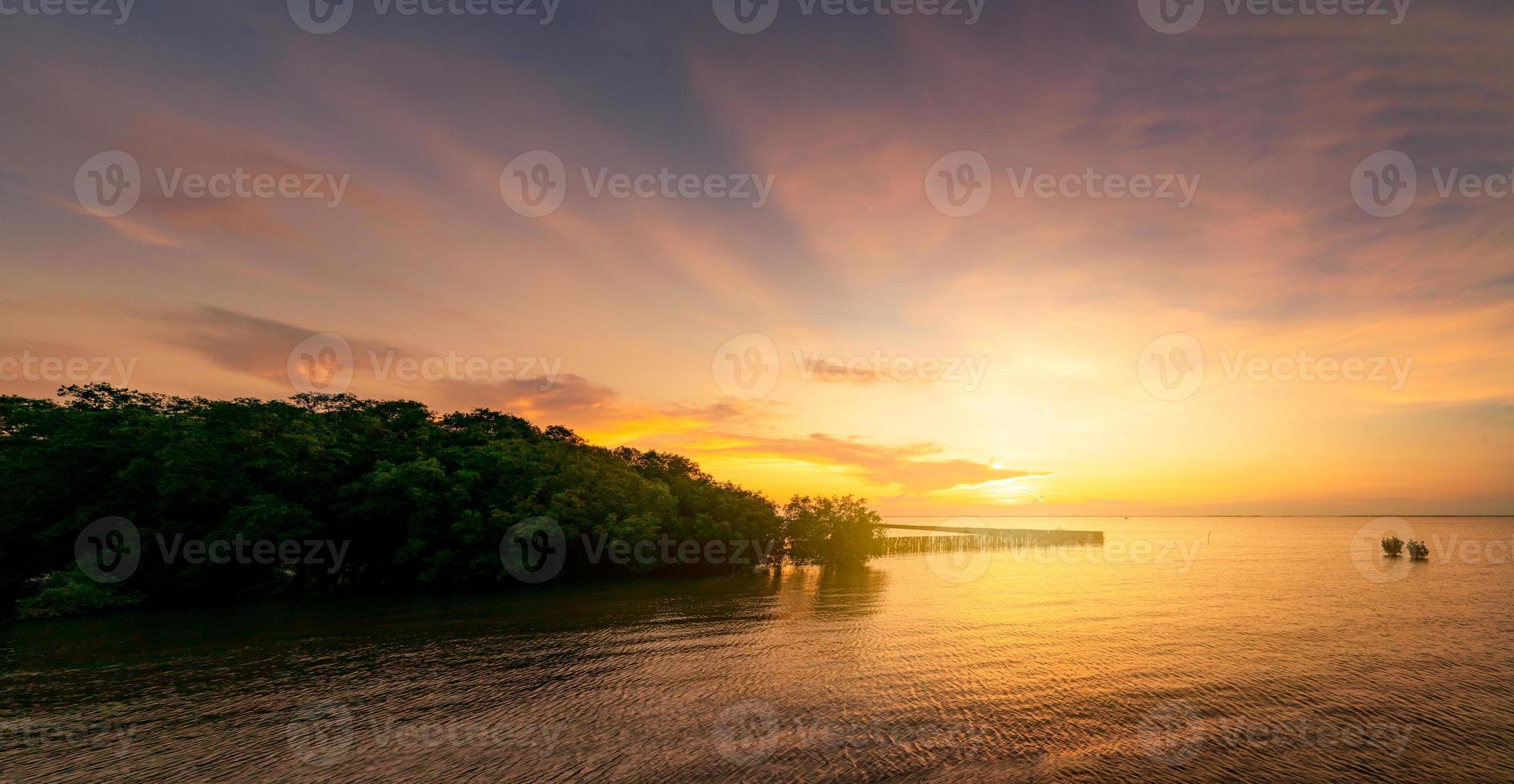 hermoso cielo de puesta de sol sobre el mar tropical cerca del bosque de manglares. cielo dorado del atardecer. horizonte en el mar. belleza en la naturaleza. vista a la playa tropical. superficie de agua de mar con poca ola. mar en calma. foto