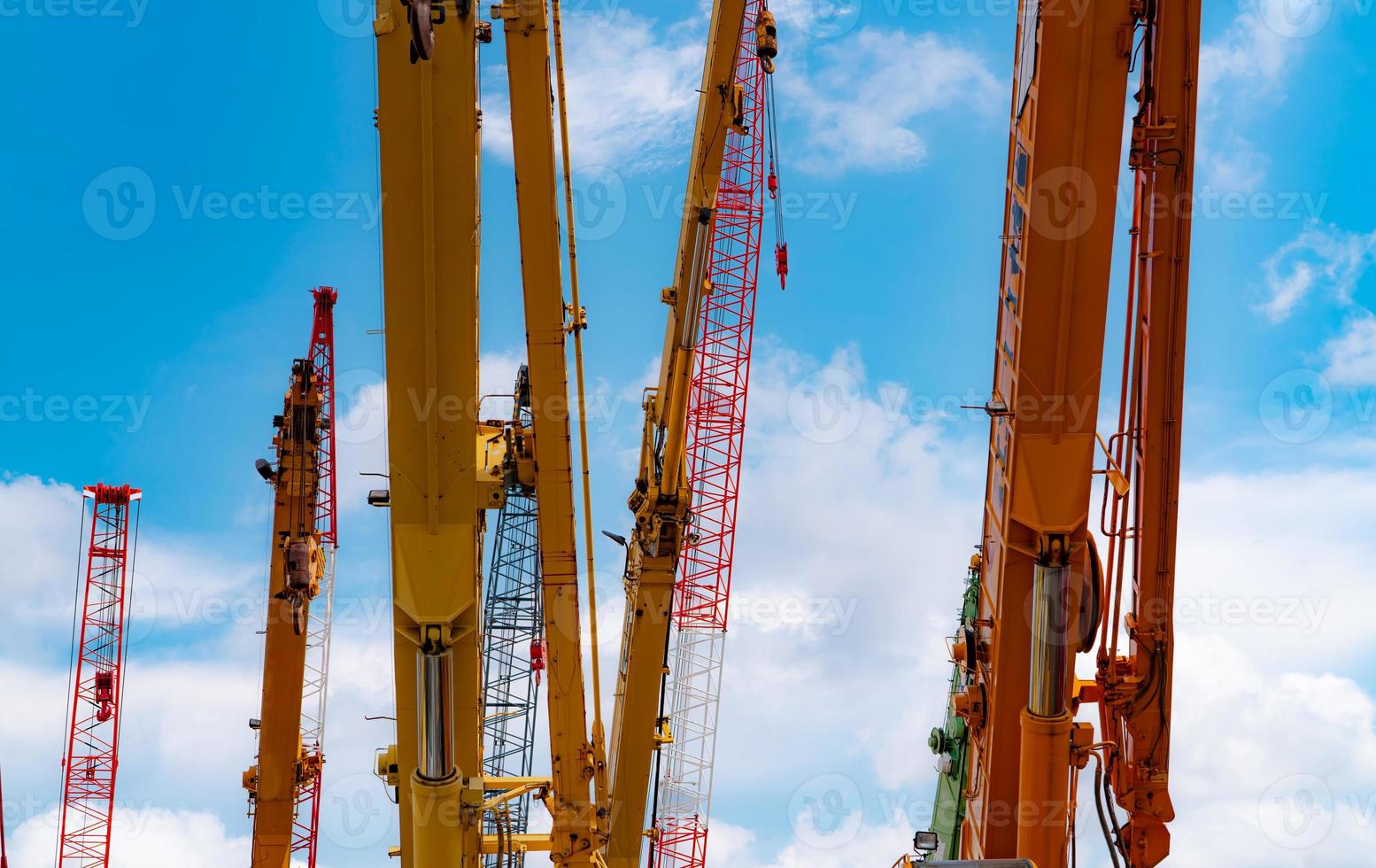 Crawler crane against blue sky and white clouds. Real estate industry. Red crawler crane use reel lift up equipment in construction site. Crane for rent. Crane dealership for construction business. photo