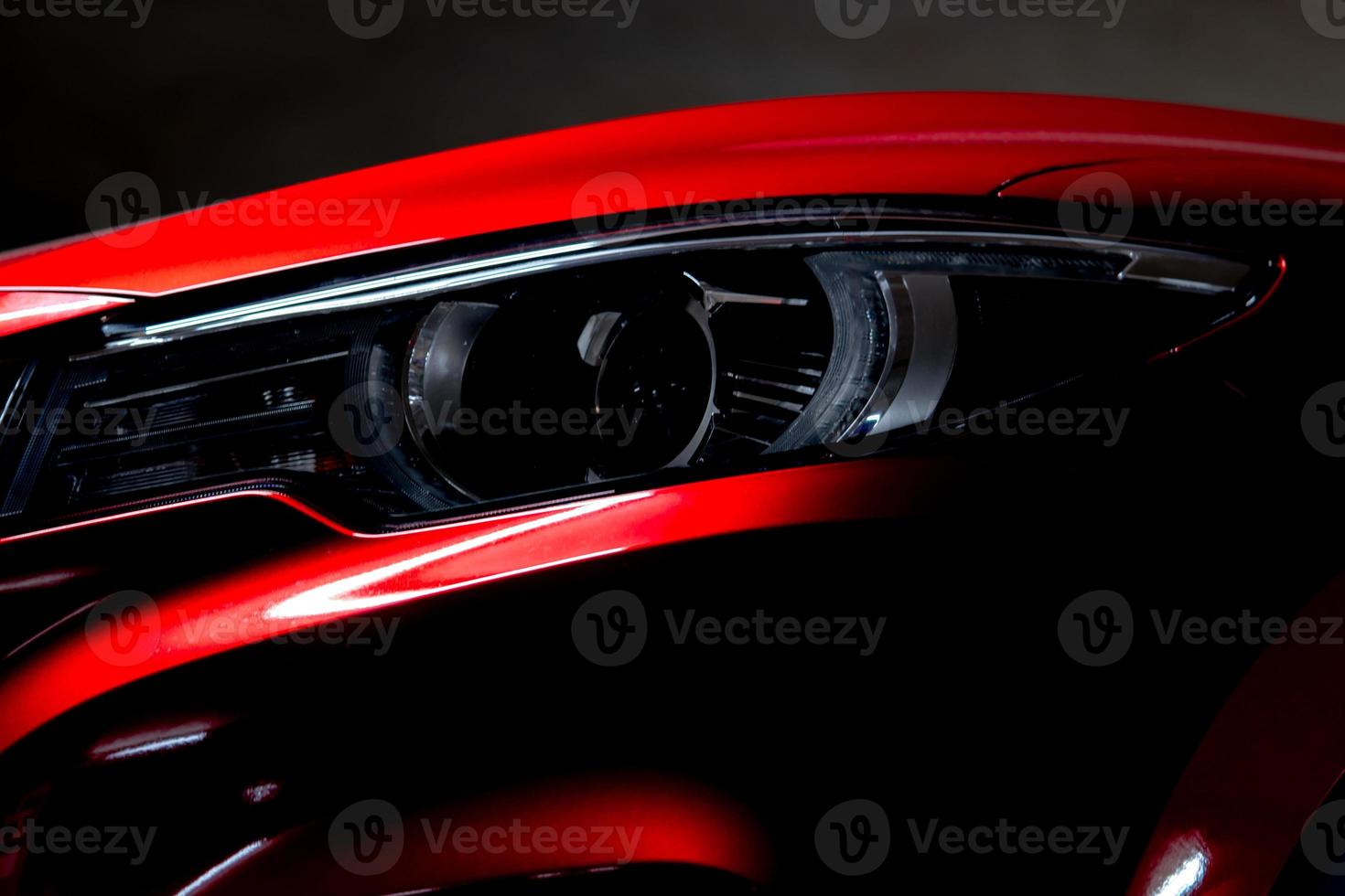 Closeup headlight of shiny red luxury SUV compact car. Elegant electric car technology and business concept. Hybrid auto and automotive concept. Car parked in showroom or motor show. Car dealership. photo