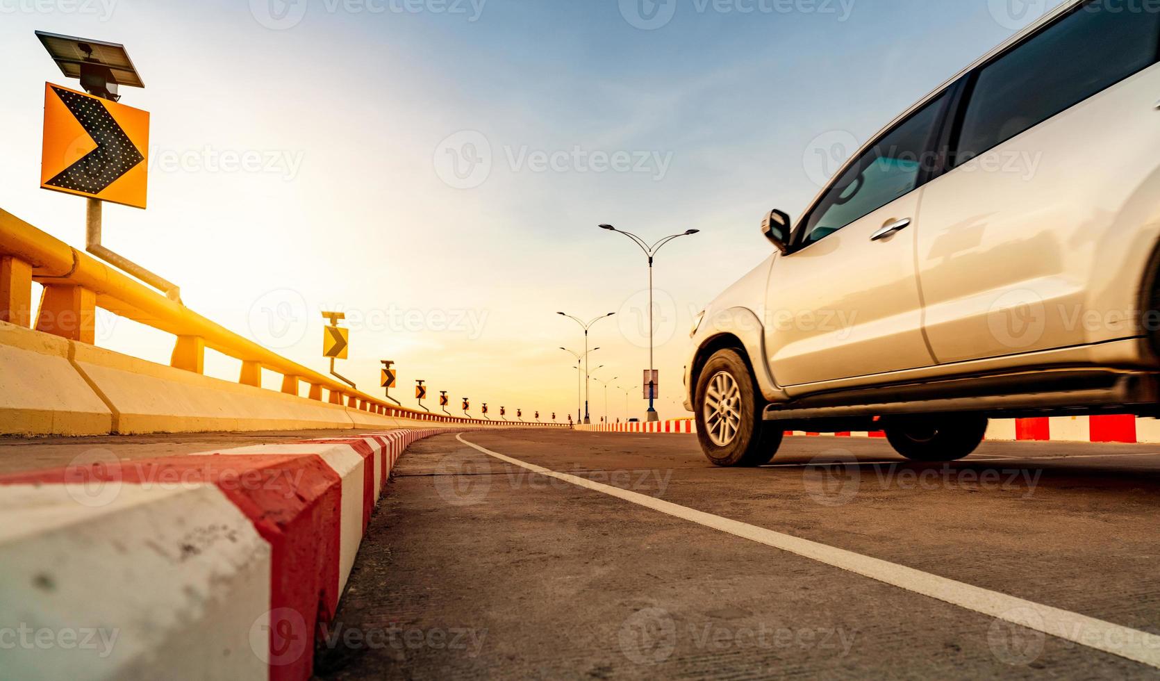 Curve concrete road with curve traffic sign and red-white prohibited stop sign. Solar panel energy on curve traffic sign. Road trip. Motion blur of white car driving on the road. Road trip on summer. photo