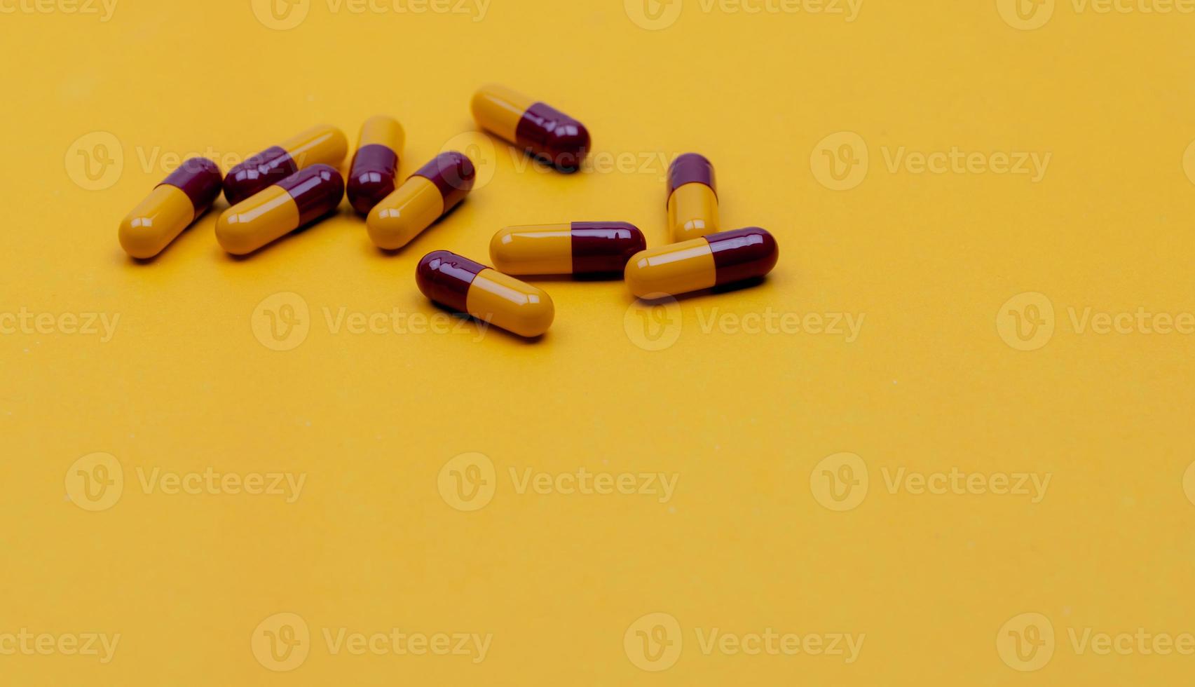 píldoras de cápsula antibiótica de color rojo-amarillo sobre fondo amarillo. medicamento con receta médica. concepto de resistencia a los antibióticos. píldoras de cápsulas de penicilina. industria farmacéutica. farmacia. producto de farmacia. foto