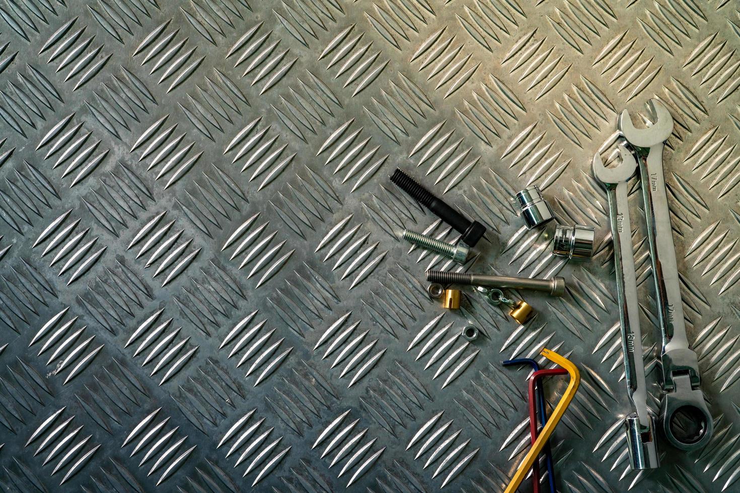 Top view of tools on industrial metal checker plate. Metal checkerplate for anti skid. Nut, bolts, and hex key on metal sheet floor. Silver bump ground with art pattern. Silver texture background. photo