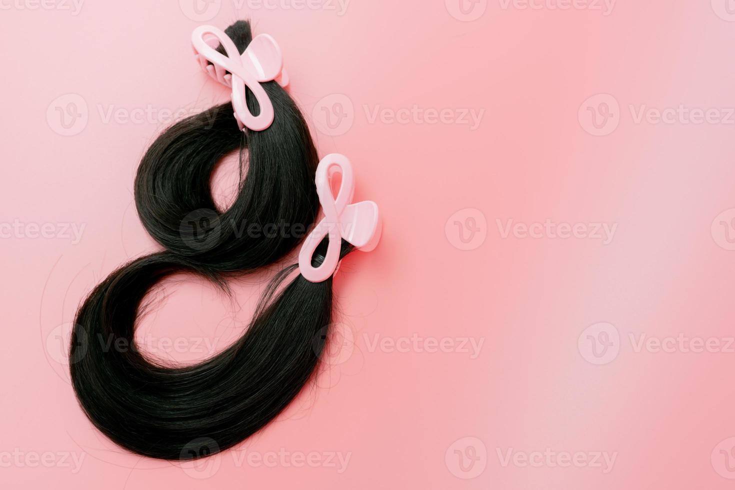 Hair donation for breast cancer person. Donate hair to wigs for breast cancer and leukemia patients. Donate to cancer charity. Long human hair with hair clip claw for donation on pink background. photo