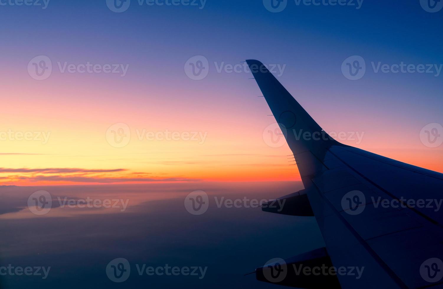 Wing of plane with sunrise skyline. Airplane flying in the sky. Scenic view from airplane window. Commercial airline flight. Plane wing above clouds. International flight. Travel abroad after covid-19 photo