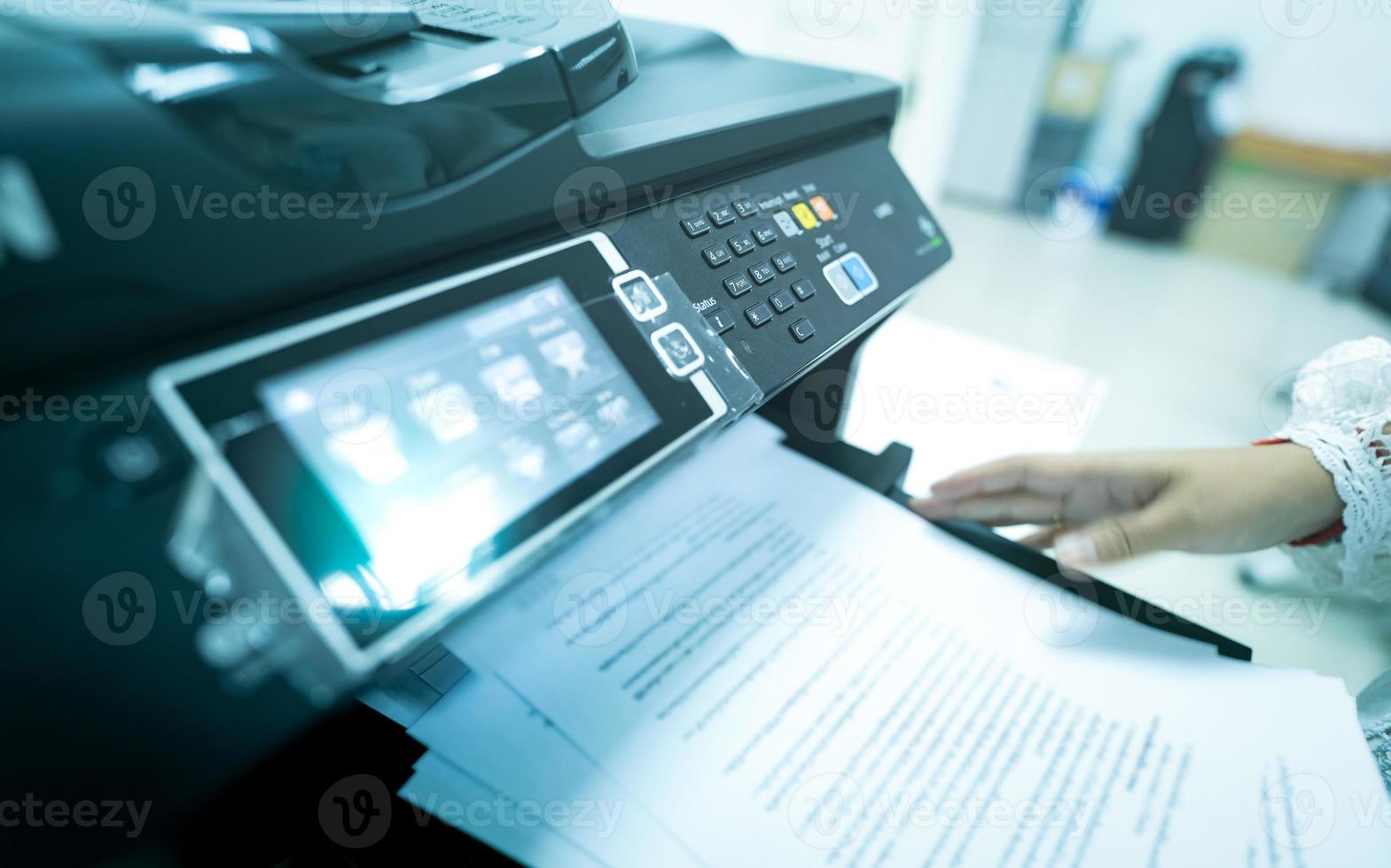 Office worker print paper on multifunction laser printer. Copy, print, scan, and fax machine in office. Modern print technology.  Photocopy machine. Document and paper work. Scanner. Secretary work. photo