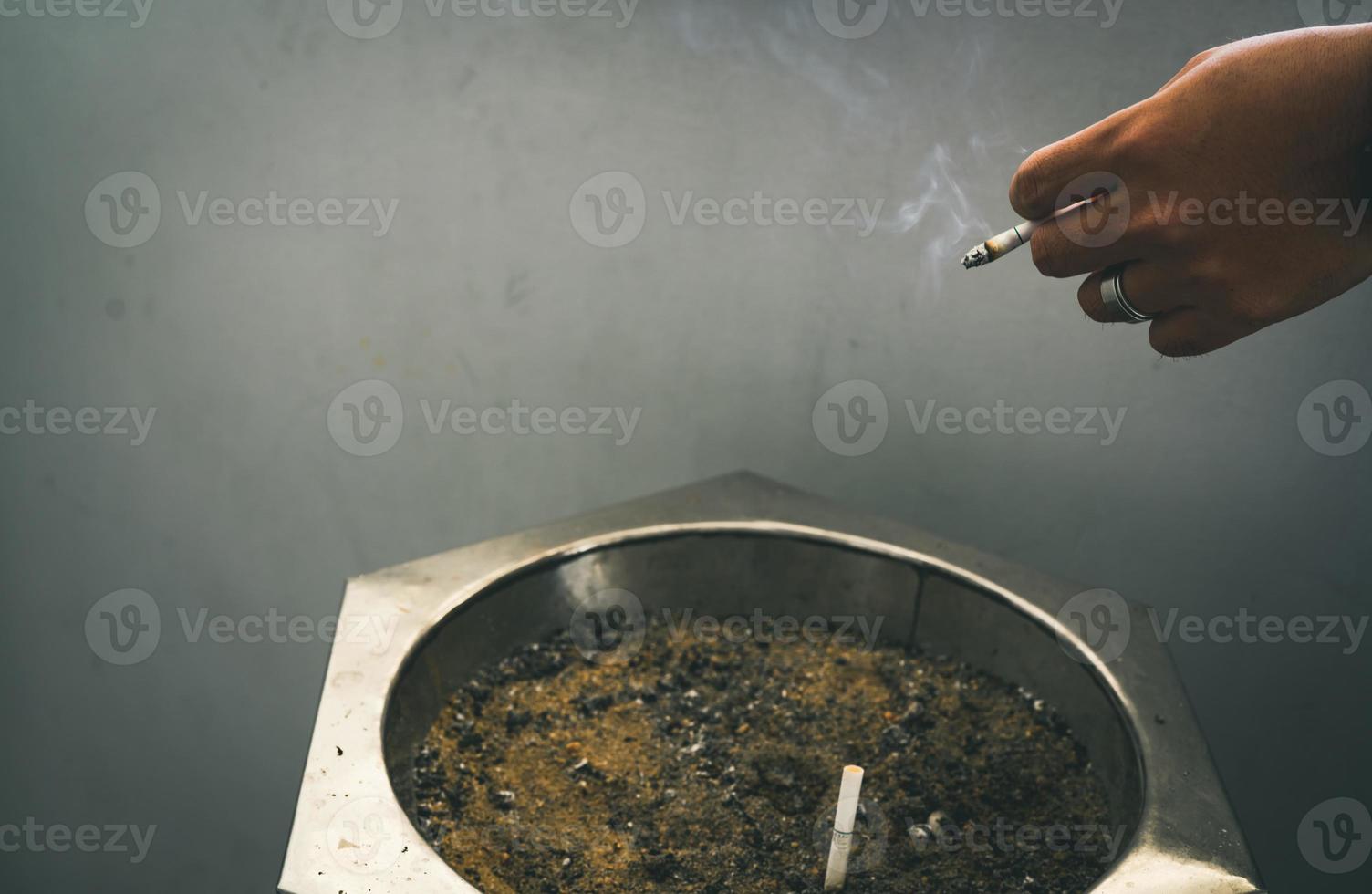 primer plano de la mano de un hombre con cigarrillo. gente fumando en la zona de fumadores del centro comercial y dejó el cigarrillo en el cenicero. dejar de fumar o dejar de fumar y cáncer de pulmón. 31 de mayo día mundial sin tabaco. foto