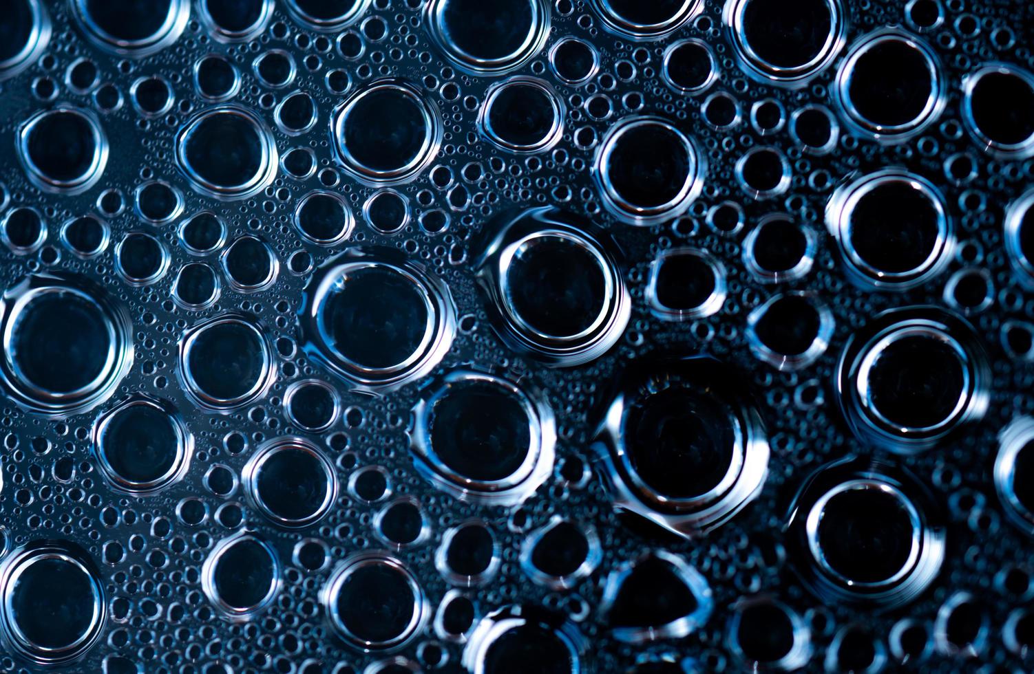 detalle de disparo macro de gotas de agua con un patrón único. fondo de textura de gotas de agua. forma redonda de gota sobre fondo oscuro. fondo abstracto de gotas de agua de diferentes tamaños. gota de agua foto