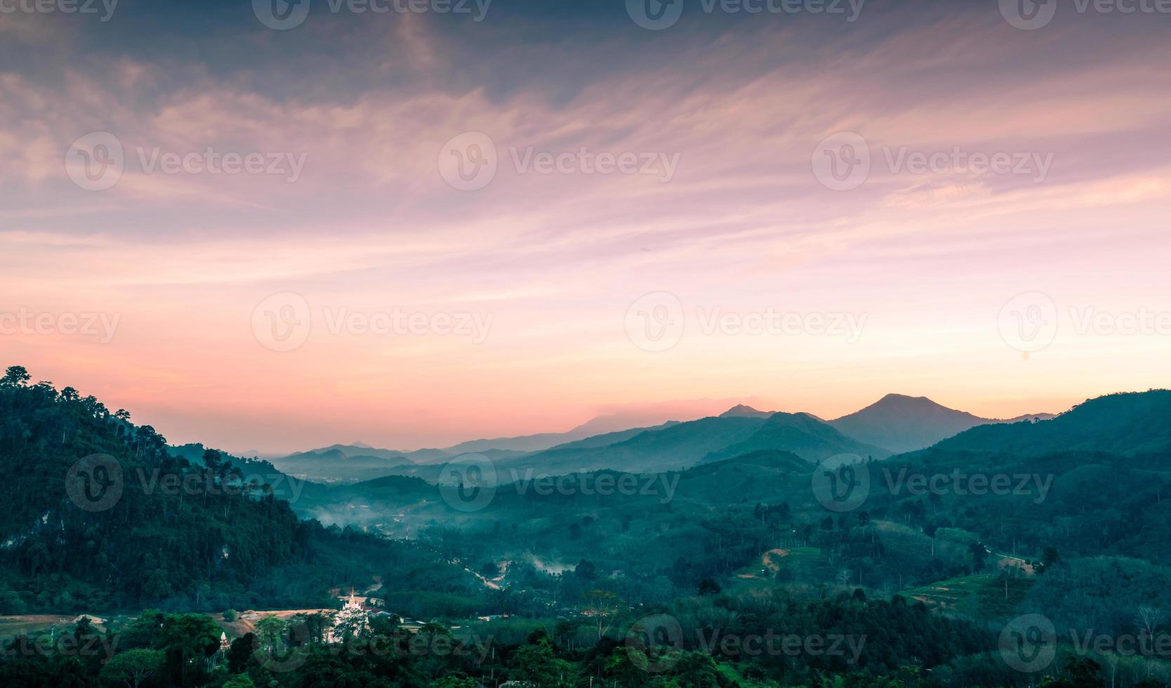 Beautiful nature landscape of mountain range with sunset sky and clouds. Rural village in mountain valley in Thailand. Scenery of mountain layer at dusk. Tropical forest. Natural background. photo