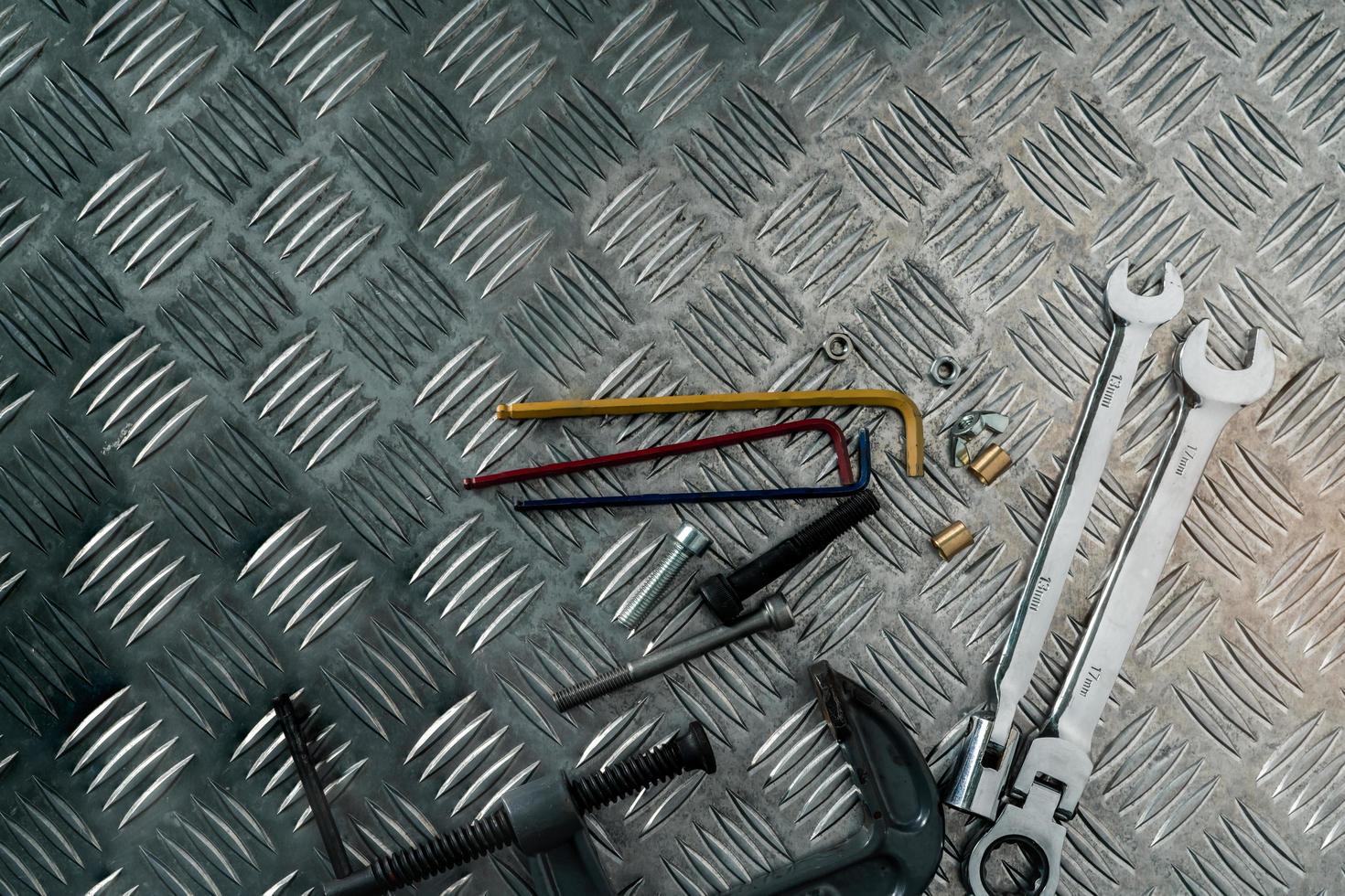 Top view of tools on industrial metal checker plate. Metal checkerplate for anti skid. Nut, bolts, and hex key on metal sheet floor. Silver bump ground with art pattern. Silver texture background. photo