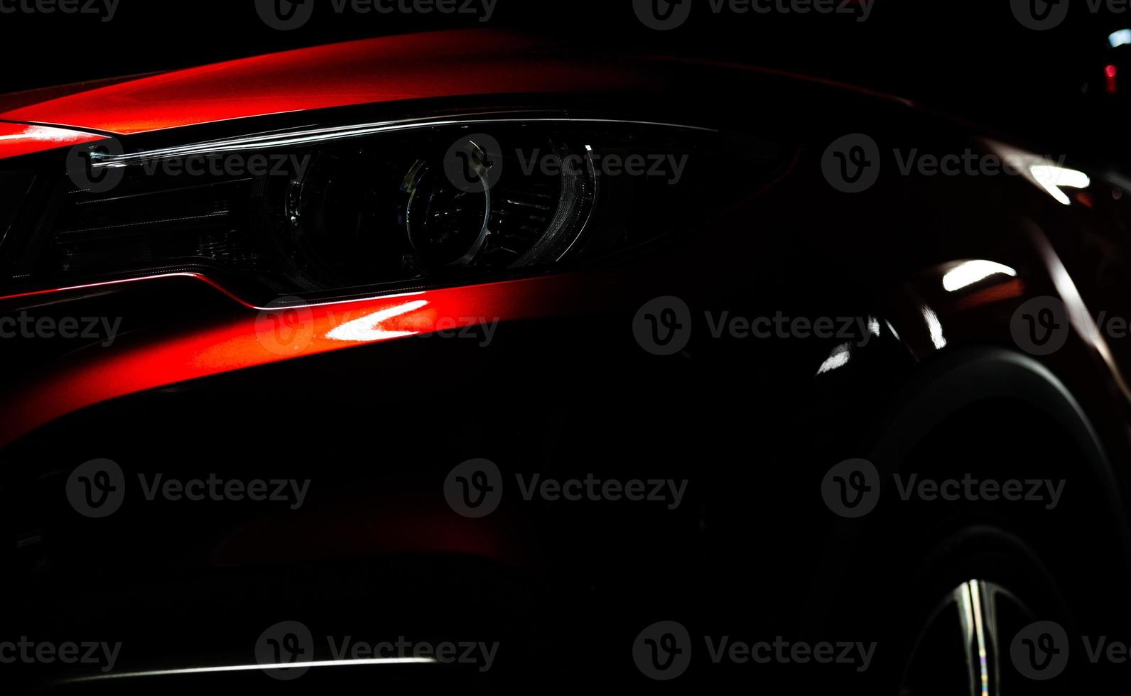 Closeup headlight of shiny red luxury SUV compact car. Elegant electric car technology and business concept. Hybrid auto and automotive concept. Car parked in showroom or motor show. Car dealership. photo