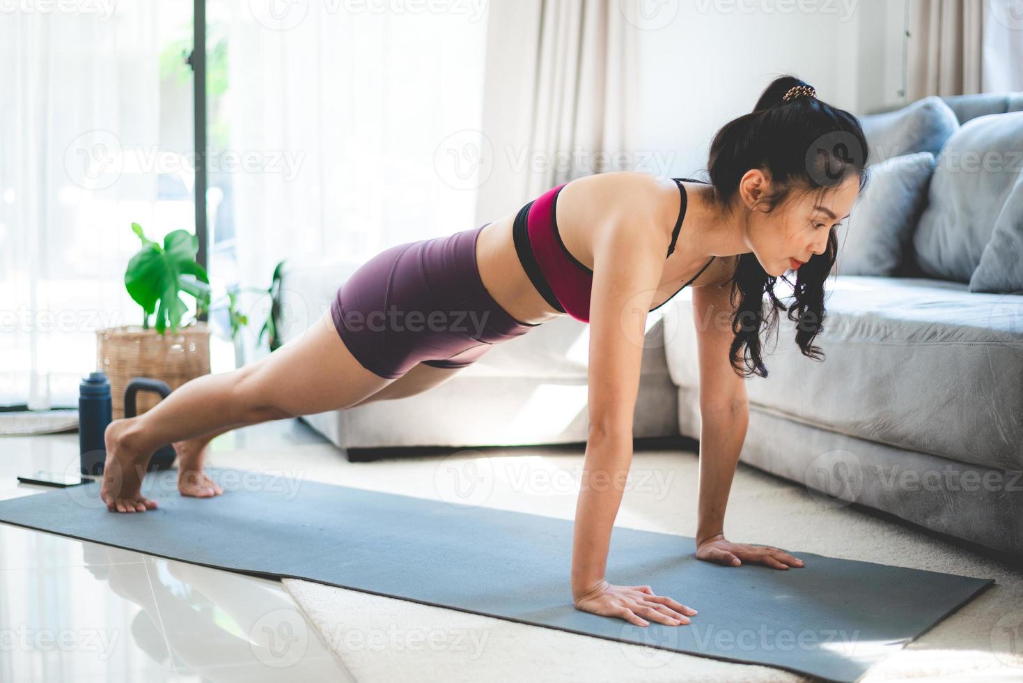 young Asian woman exercise by yoga at home gym, healthy female lifestyle with fitness sport training at home, girl doing body active physical exercise indoor house room, relaxation and wellness photo