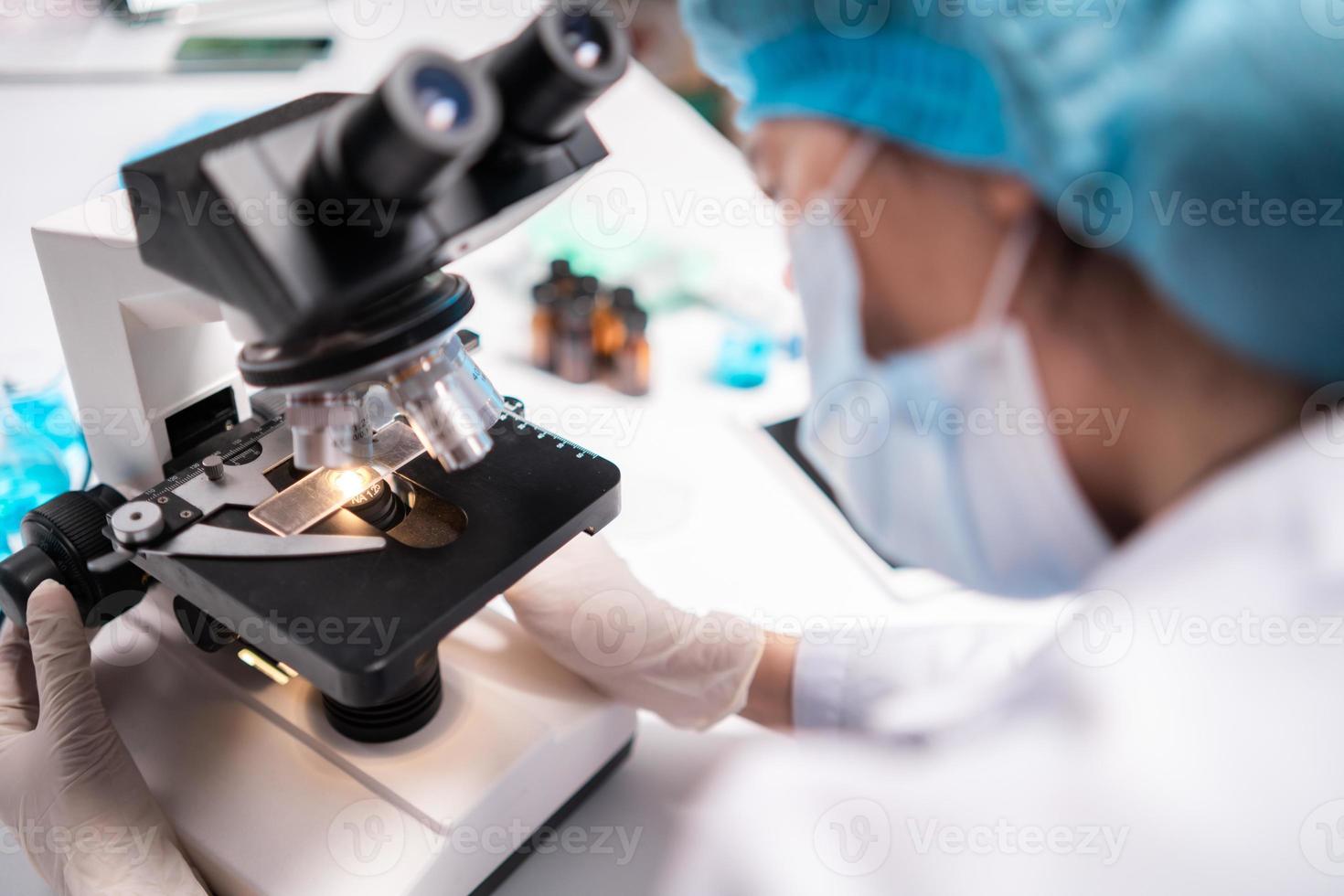 scientist looking through scientific microscope lense in laboratory, scientist doing research in term of medicine biotechnology biology or chemistry, doctor analyzing work in medical microbiology lab photo