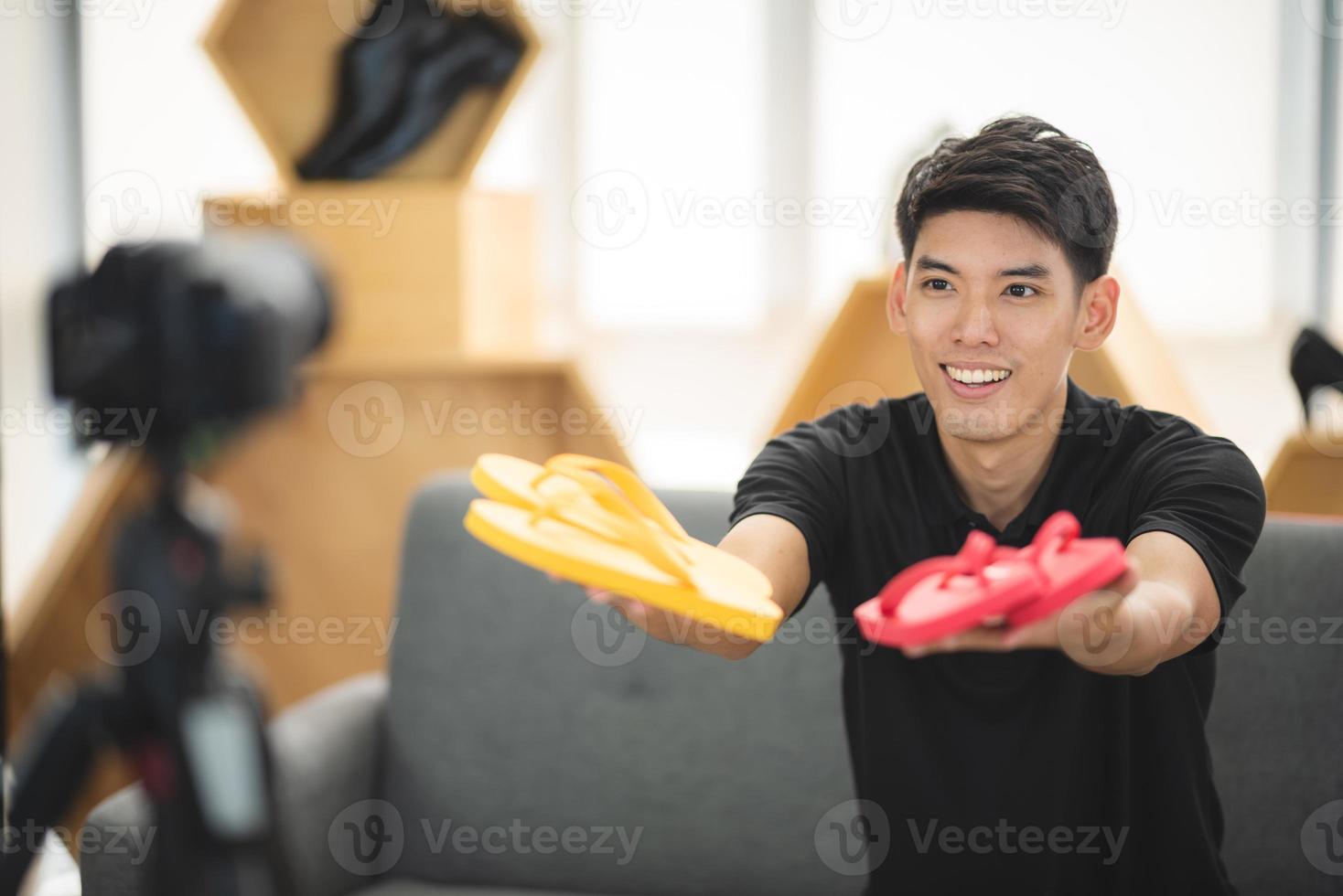 online sale and social media marketing concept, young Asian man working with camera to live streaming to sale a product and showing packet to review, broadcast cyberspace and blog shop photo