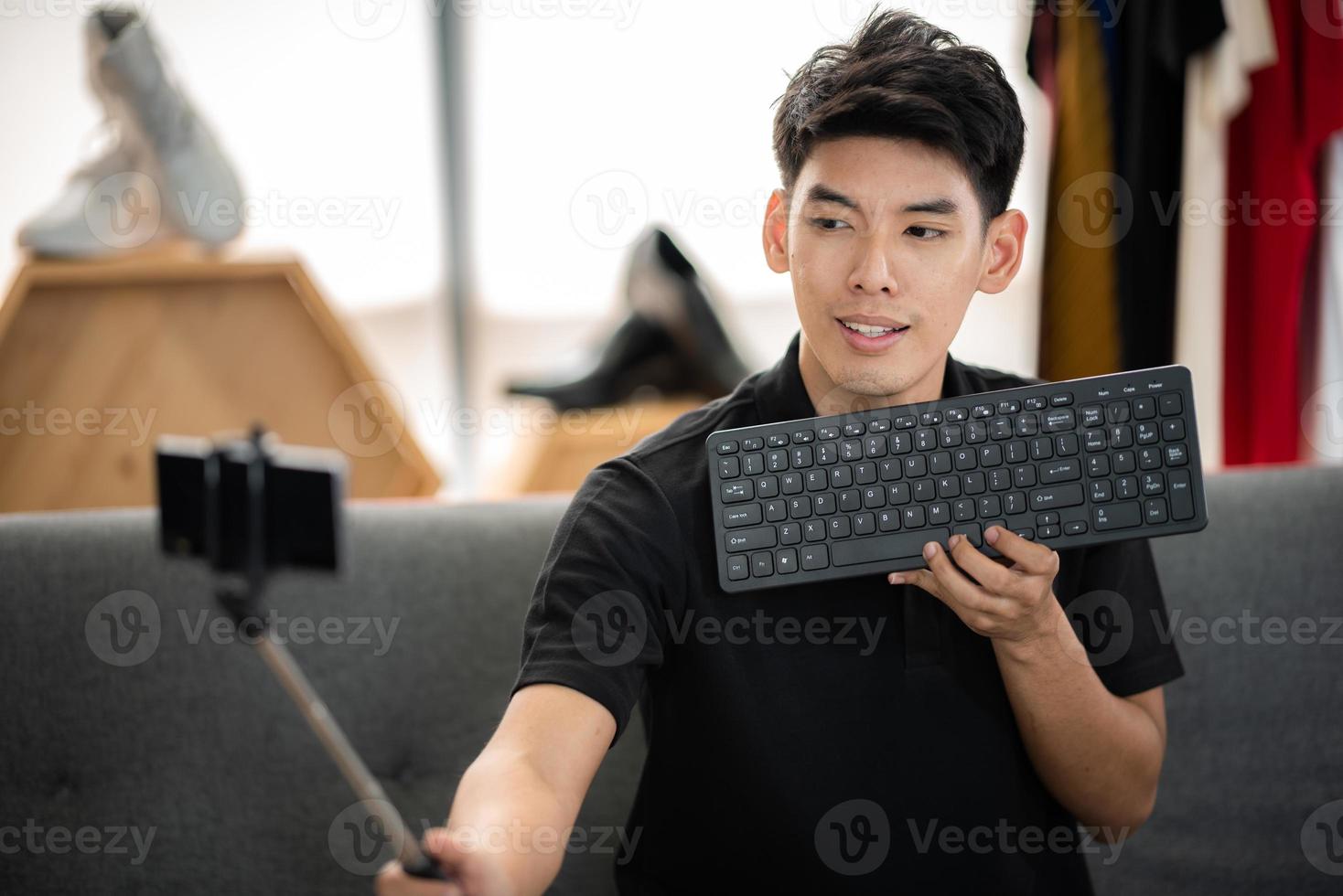 online sale and social media marketing concept, young Asian man working with camera to live streaming to sale a product and showing packet to review, broadcast cyberspace and blog shop photo