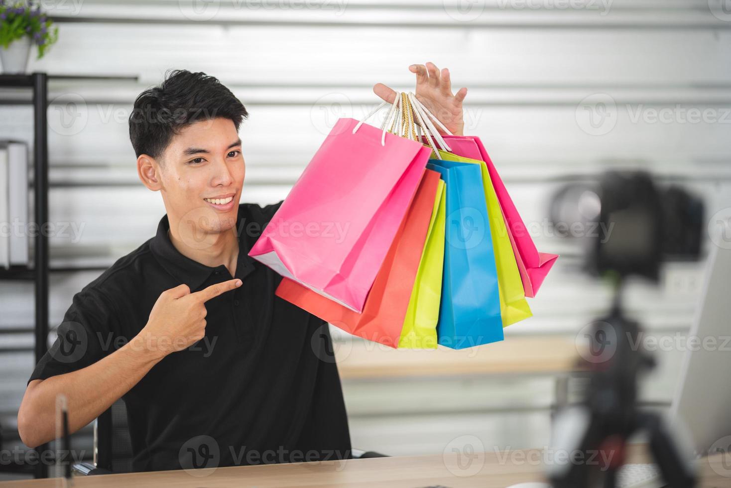 online sale and social media marketing concept, young Asian man working with camera to live streaming to sale a product and showing packet to review, broadcast cyberspace and blog shop photo