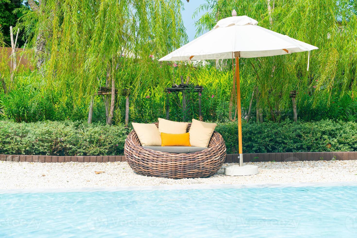 outdoor patio chair with pillow and umbrella around swimming pool photo