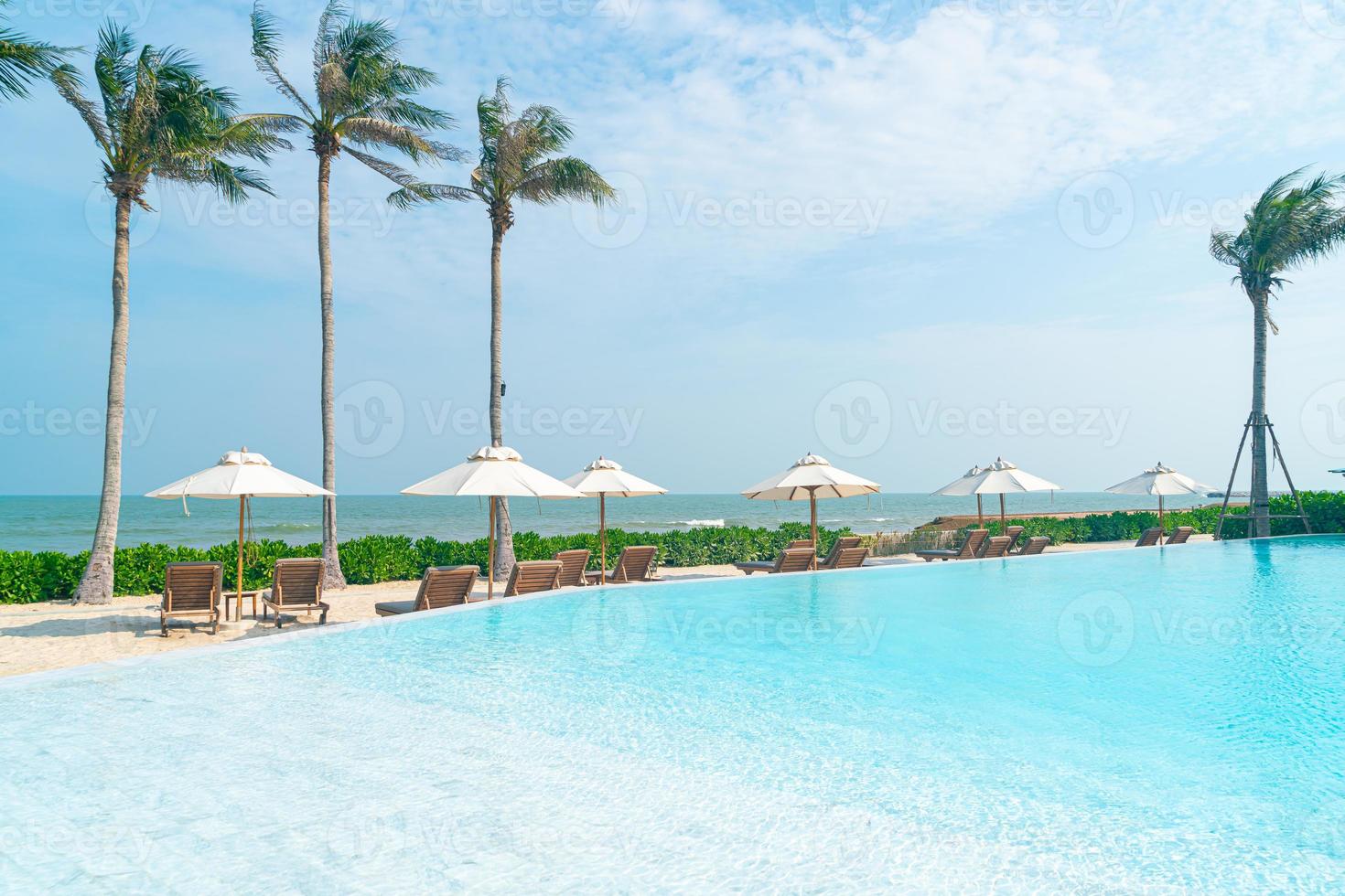 sombrilla con cama piscina alrededor de la piscina con fondo de mar océano foto