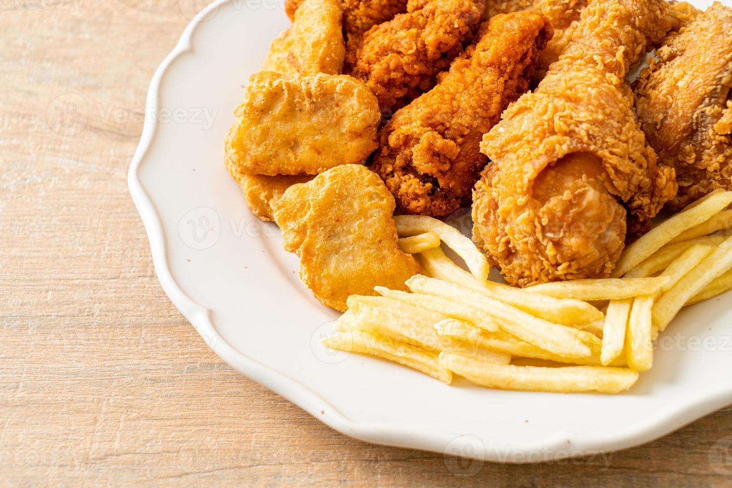 pollo frito con papas fritas y nuggets en un plato foto