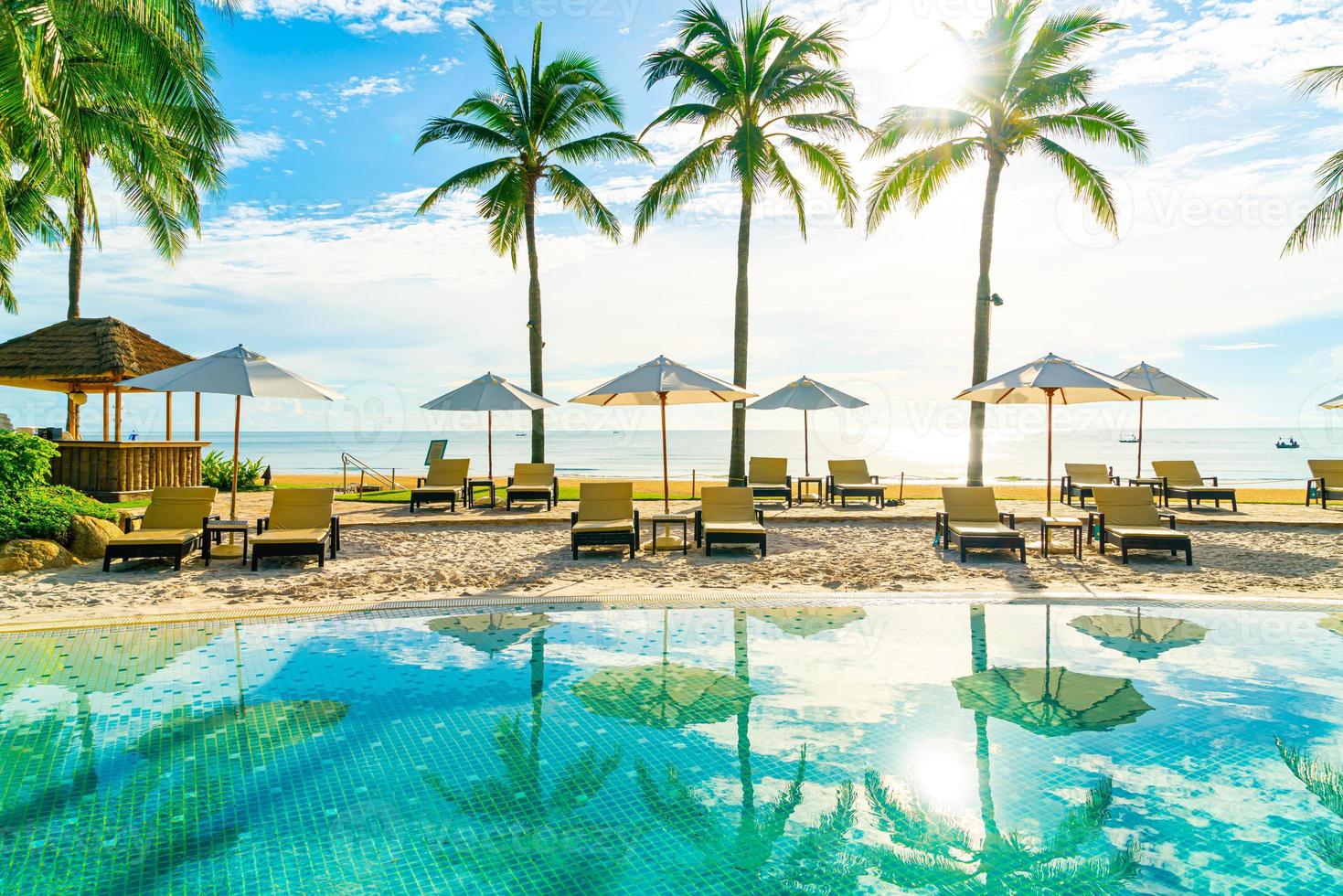 Beautiful luxury umbrella and chair around outdoor swimming pool in hotel and resort with coconut palm tree on blue sky photo