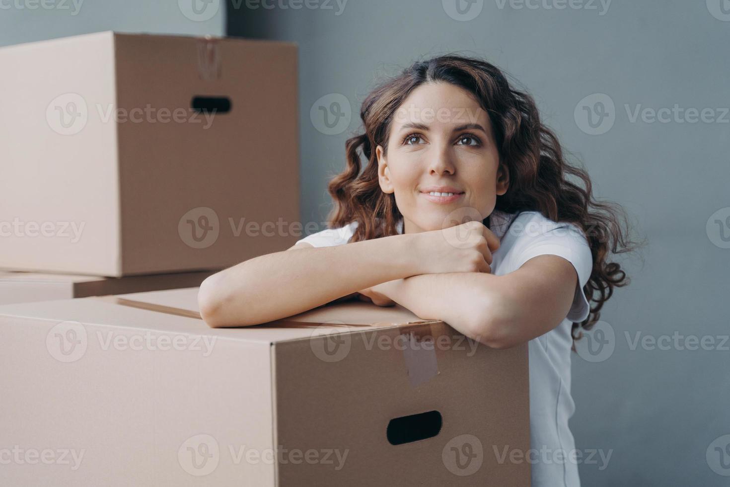 cara de una joven española que sueña sentada en el suelo en un nuevo apartamento o casa. foto