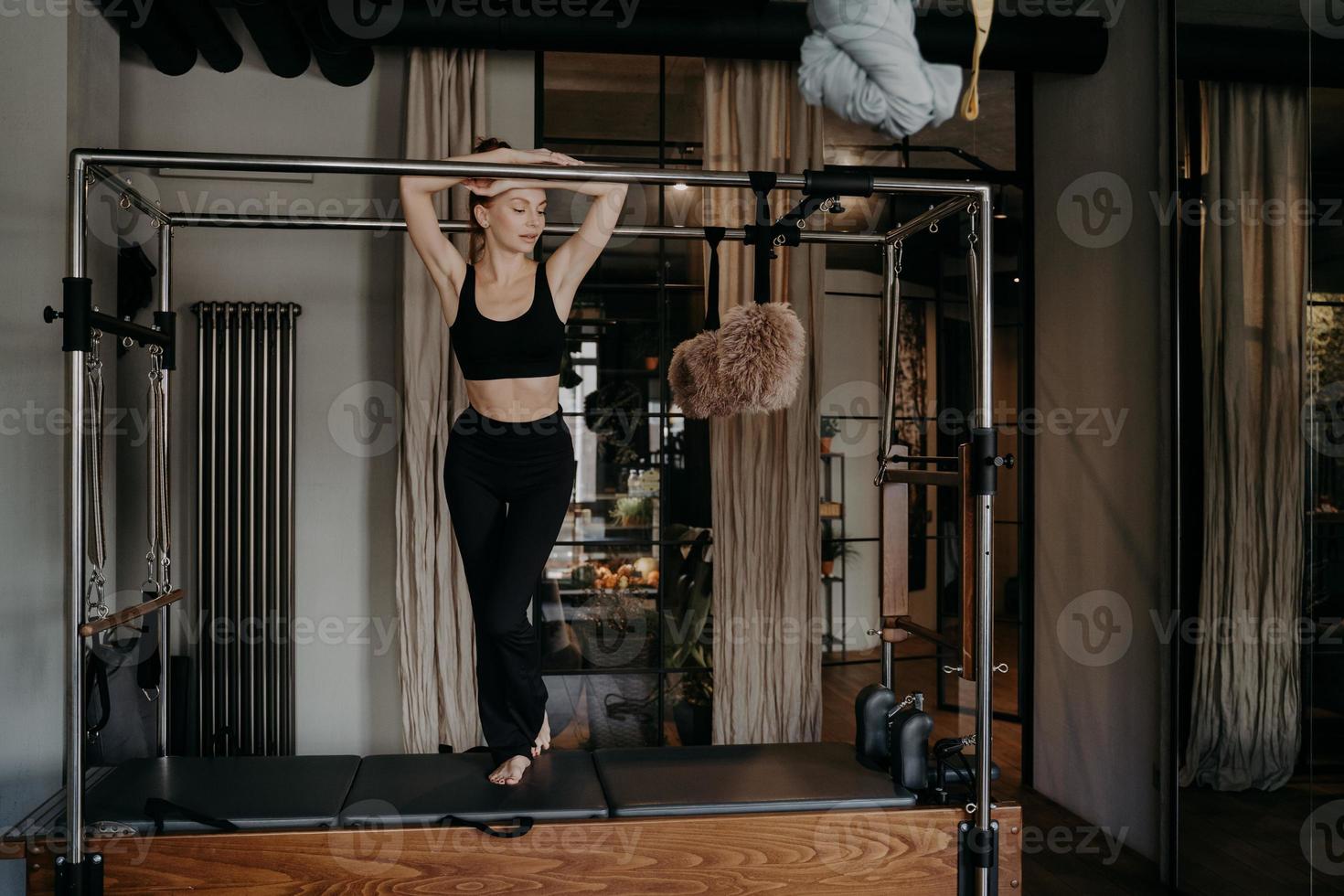 Joven mujer caucásica delgada descansando en la barra de pilates cadillac reformer foto