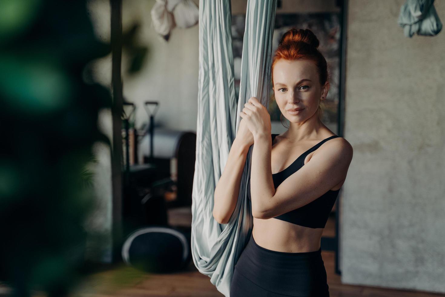 Young woman being ready for antigravity yoga exercises in studio, looking in camera photo