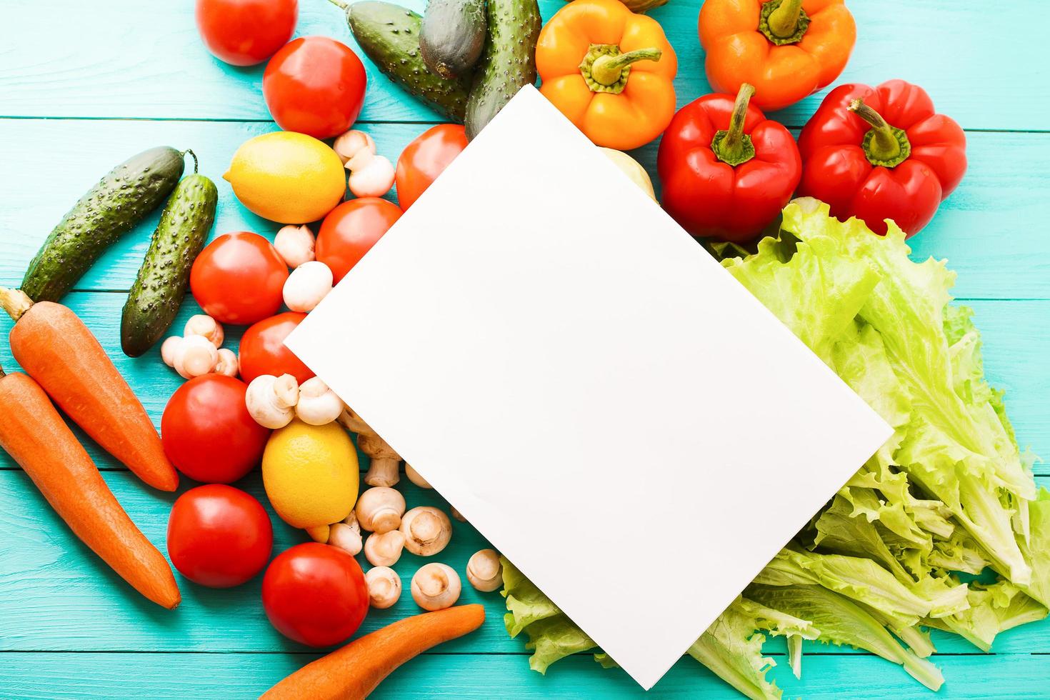 Recipe paper with vegetables on blue table. Top view photo